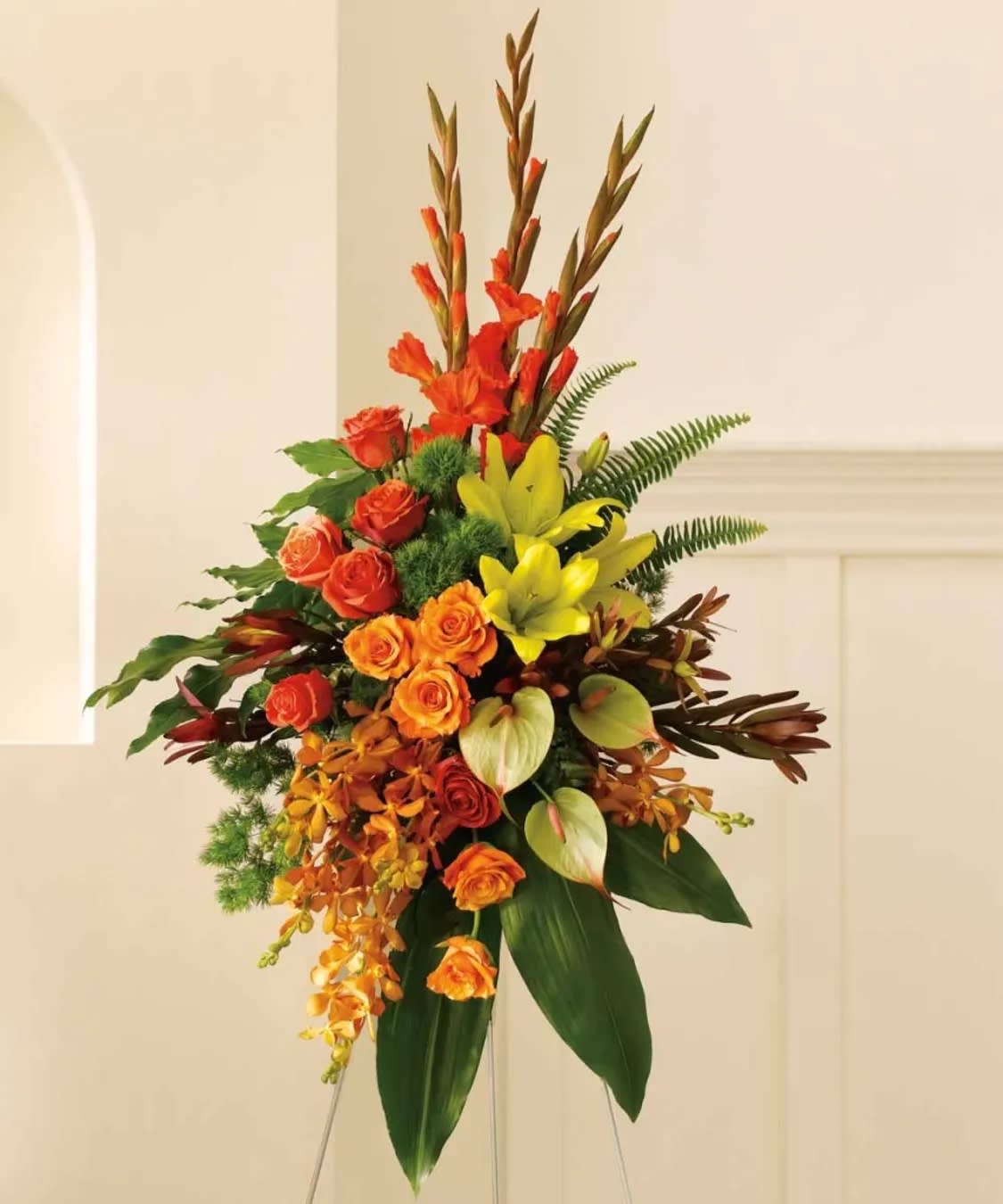 Tropical Tribute Spray - TROPICAL TRIBUTE SPRAY A graceful modern funeral spray of warm colors, it includes flowers such as anthuriums, roses and tropical greenery. Presented as a standing easel display. This standing spray on a wire easel includes tropical flowers such as orange orchids, roses and red gladioli. It also may include asiatic lilies, anthuriums, tropical ferns and leaves. Approximately 29&quot; W x 46&quot; H