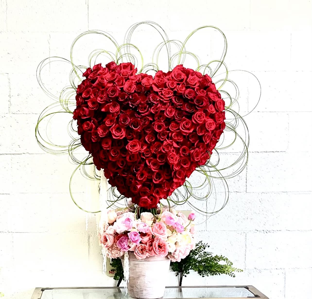 Heart-Stopper - An impressive burgundy heart blooming from a flower pot of pink spring flowers. 