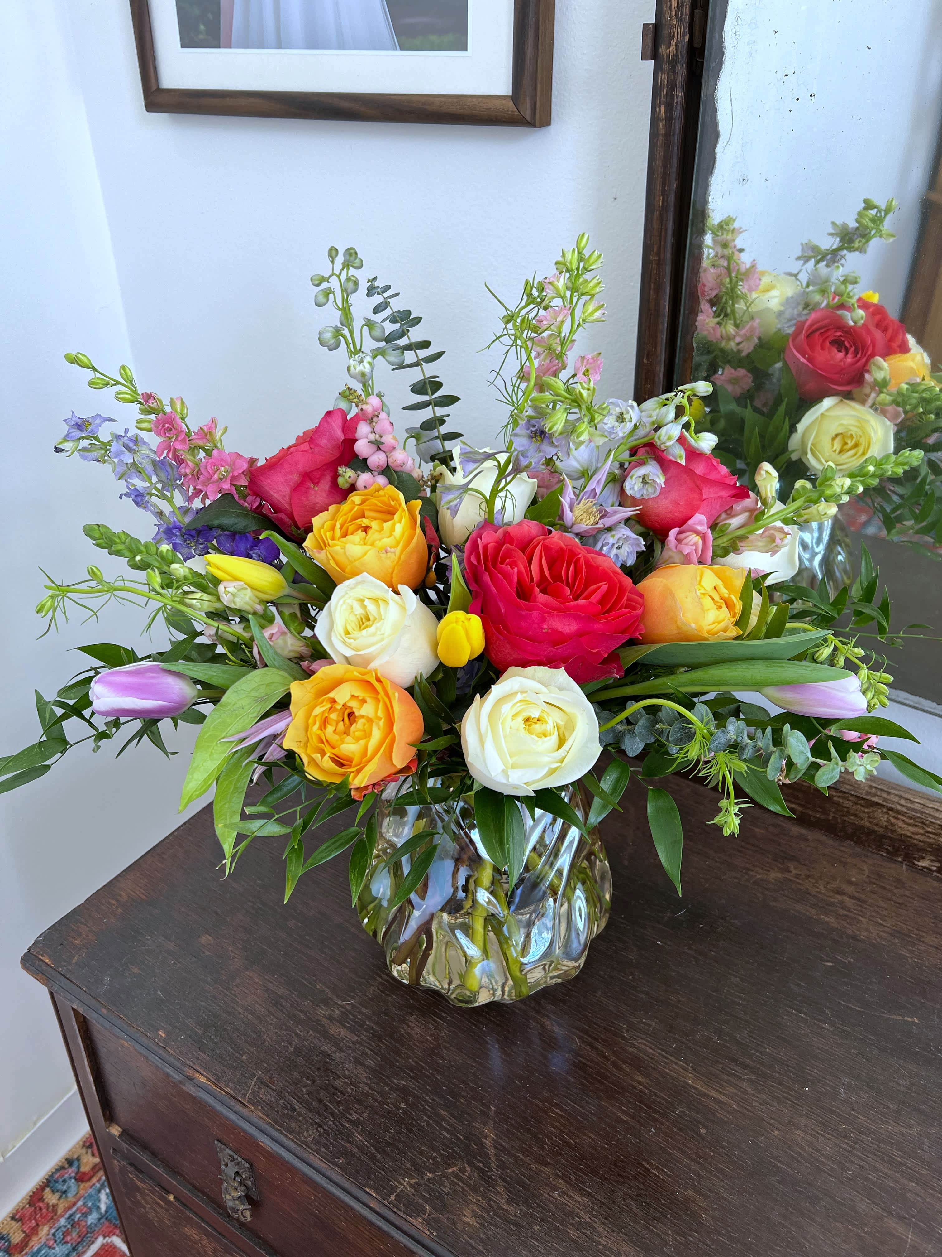 Spring Sentiments - Don’t show up to dinner empty handed! We have the perfect arrangement for a spring table centerpiece. The freshest spring pallet florals arranged medium height in a gorgeous amber/clear special tapered vase. 