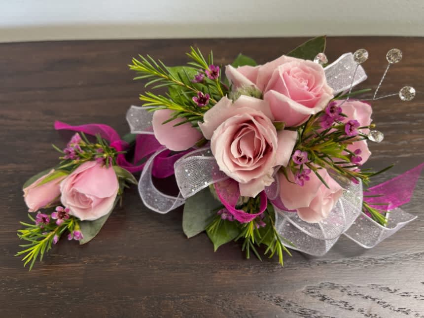 Lovely - Sweet light pink roses with pink wax flowers and a bit of bling. This is a two piece set including one corsage and one boutonniere. Ribbon, wristlets, and colors can be customizable upon request.