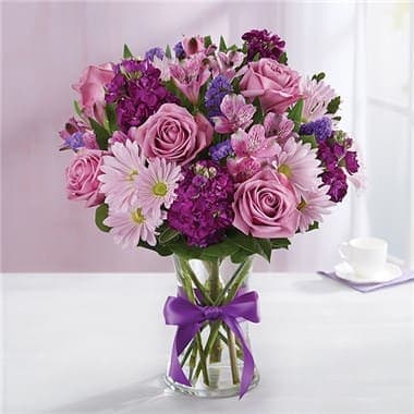 1-800-Flowers® Lavender Dreams™ In Clear Vase 1-800-Flowers® Lavender Dreams™ In Clear Vase - Here’s a delightful surprise we’ve dreamed up just for you. Our expert florists gathered lavender & purple blooms with lush greenery, creating a lovely contrast of color. It’s all designed inside our striking violet purple vase to capture its rich beauty, along with the thoughtfulness of your sentiment. • All-around arrangement with lavender roses and daisy poms; purple Peruvian lilies (alstroemeria), stock and statice; accented with assorted greenery • To ensure lasting beauty, Peruvian lilies may arrive in bud form, and will fully bloom over the next few days • Our florists select the freshest flowers available, so colors and varieties may vary due to local availability • Artistically designed in our violet purple glass vase; measures 8"H • Extra-large arrangement measures approximately 17"H x 14"L • Large arrangement measures approximately 15"H x 13"L • Medium arrangement measures approximately 14"H x 12"L • Small arrangement measures approximately 13”H x 10”L