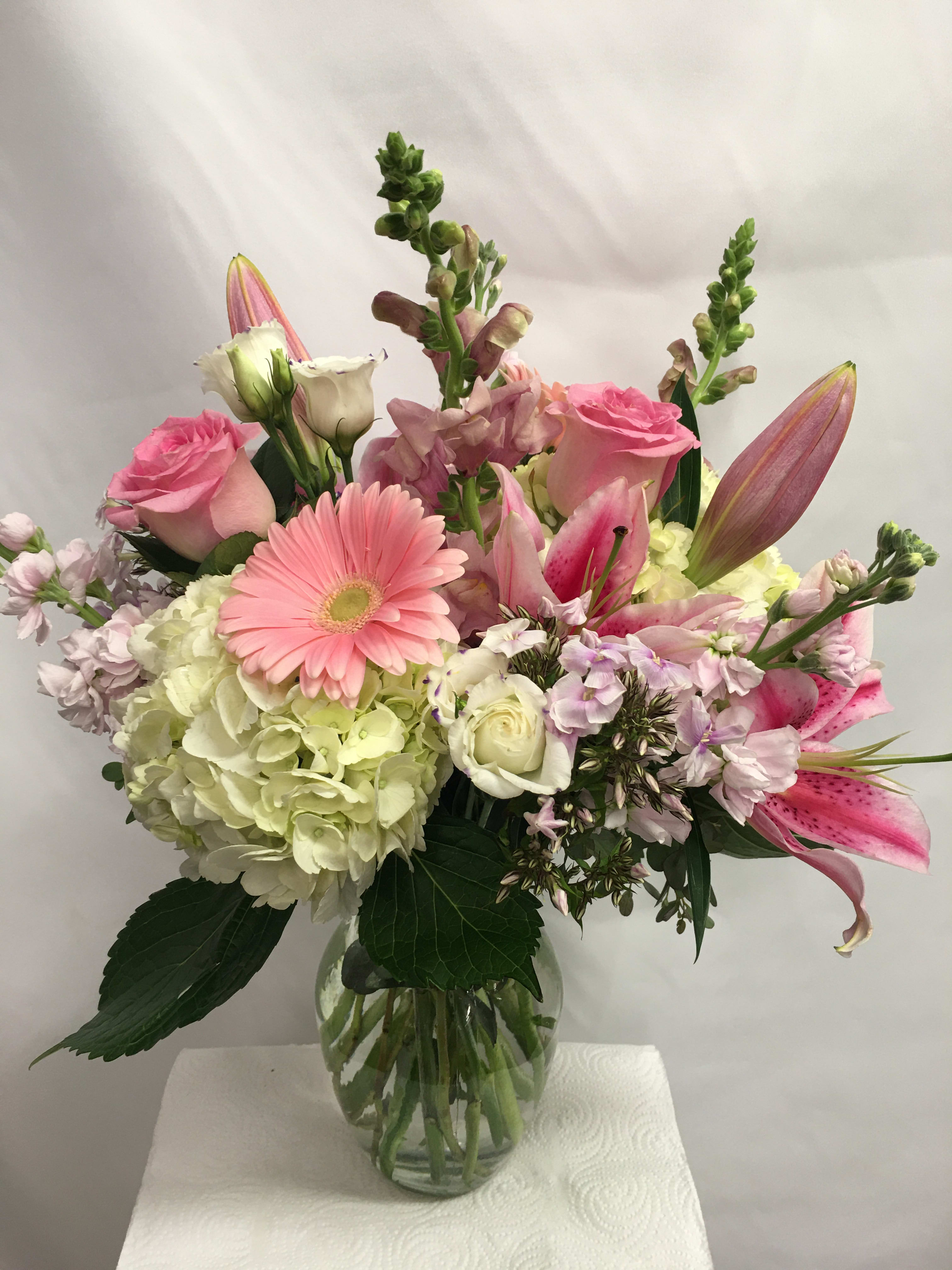 Sweet Pastels  - This vase of flowers is soft and elegant. It is lovely with an assortment of pastel seasonal flowers that include Snap Dragons, Lilies, Roses, Hydrangea &amp; Stock and other complimenting flowers throughout. 