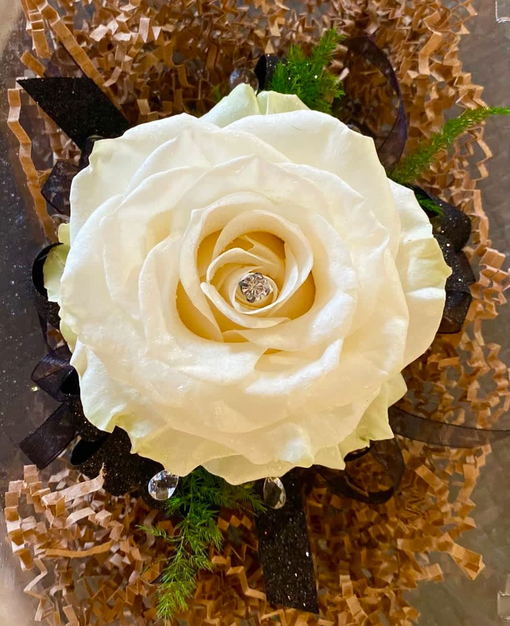 Single White Rose wrist corsage Single White Rose wrist corsage - This wrist corsage is composed of a single full-bloom white rose, accented with foliage, your choice of corsage accents, and your choice color of ribbon. This design can be created in any color of your choice.