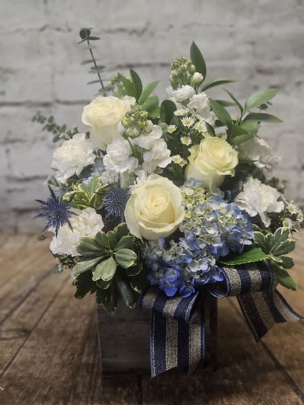 Blue Skies Blue Skies - A rustic wooden box holds a refreshing assortment of blue hydrangea, white roses, fragrant stock and carnations trimmed with a linen ribbon.