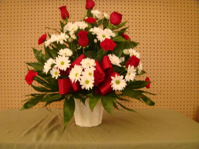 SYA07 Sympathy Basket Of Reds &amp; whites - Sympathy Basket $90.00 Consisting Of Red Roses, Red Carnations, white Daisies&amp; Jade In a mache container Complimented with A red Bow. 