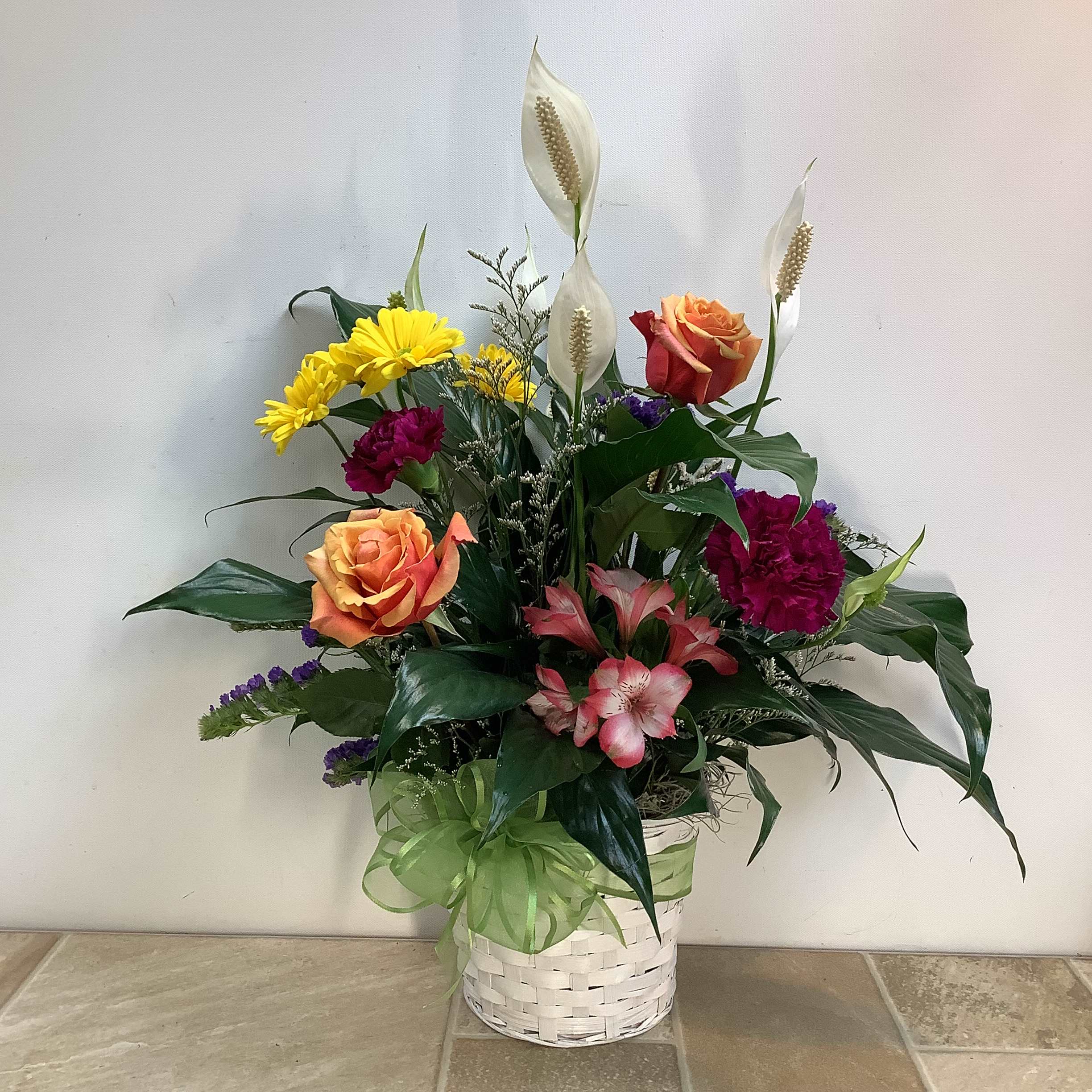 Peace Lily with Fresh Flowers - This beautiful arrangement features a live peace lily plant in a white wicker basket. We’ve enhanced it with a colorful variety of fresh flowers including roses, alstroemeria, carnations and daisies. It measures 19” wide x 24” tall. 