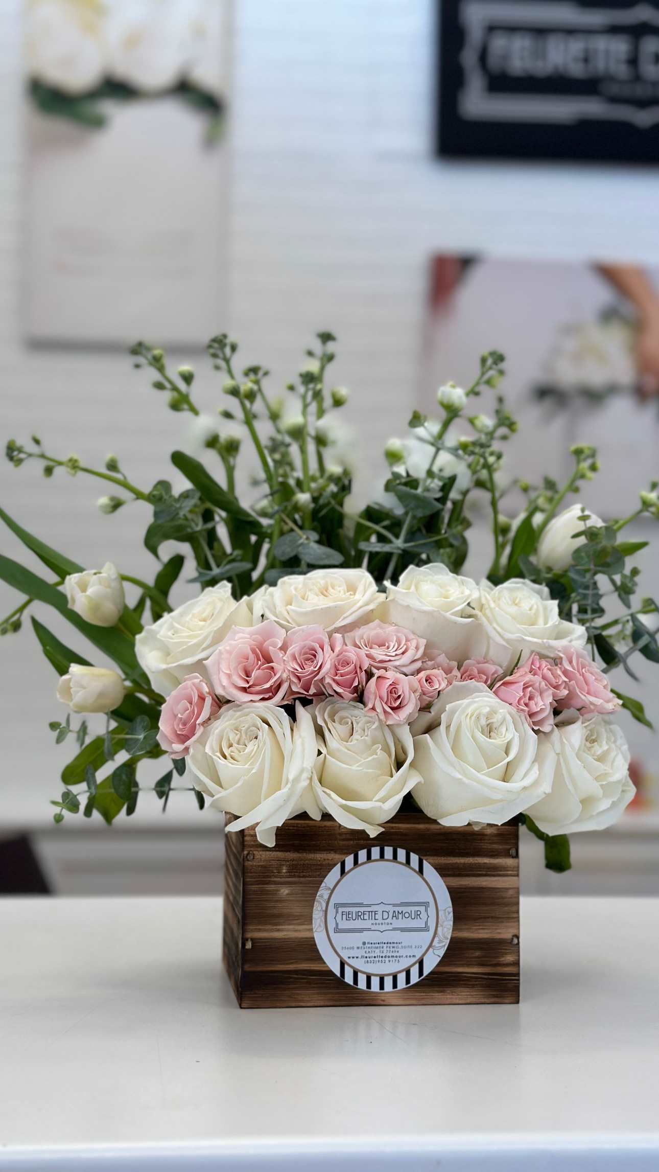 CELIA PINK -  Introducing &quot;Celia,&quot; a wooden box arrangement featuring 10 white roses, light pink baby roses, and white stock flowers.  Experience the charm of &quot;Celia&quot; with its elegant combination of flowers. Order now to add a touch of sophistication to any space with this exquisite wooden box arrangement.