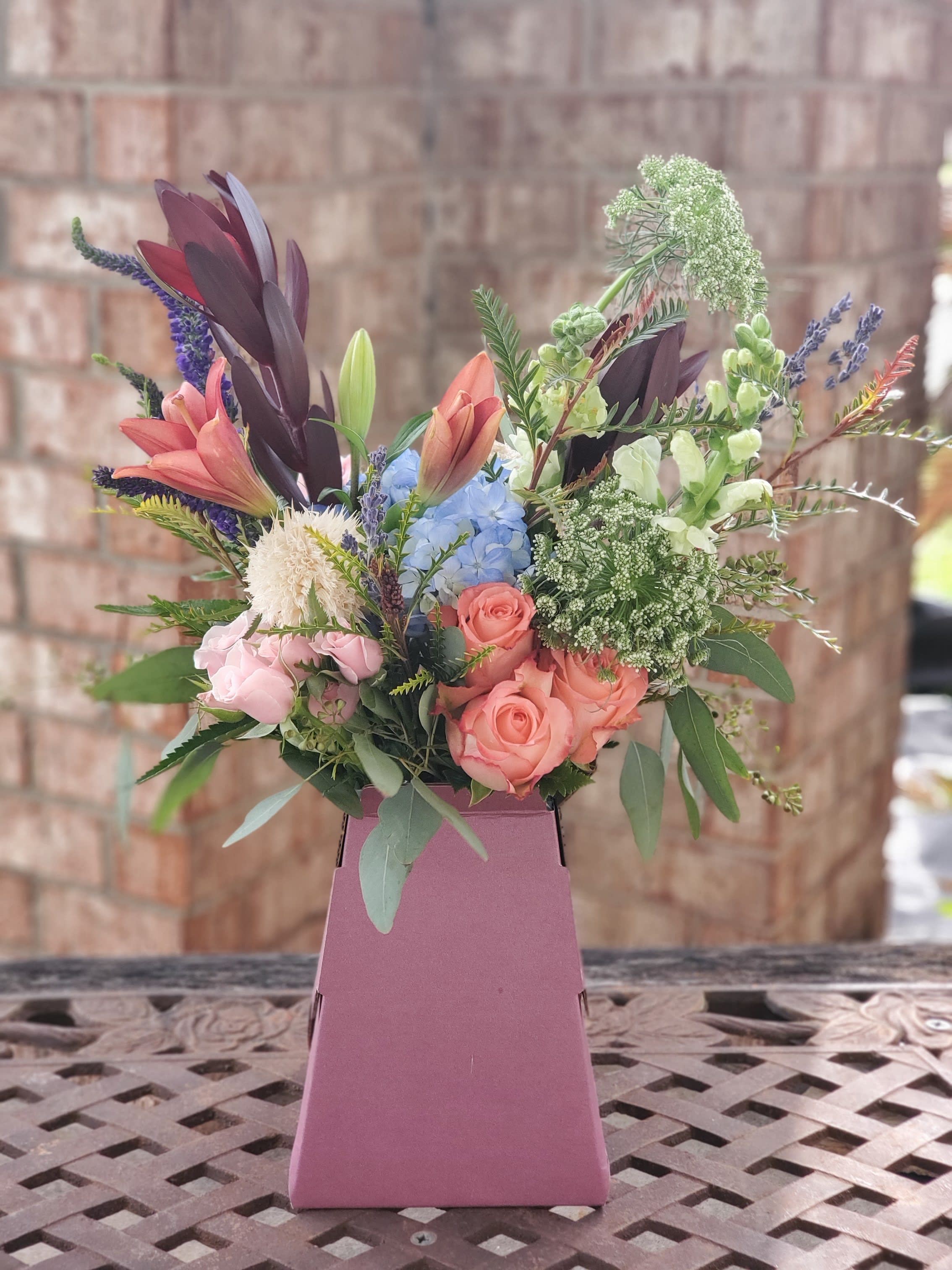 Just Say Yes - Inspired by modern style and wedding bouquets, this arrangement uses rustic colors of roses, stock, and larkspur in a recyclable cardboard vase.