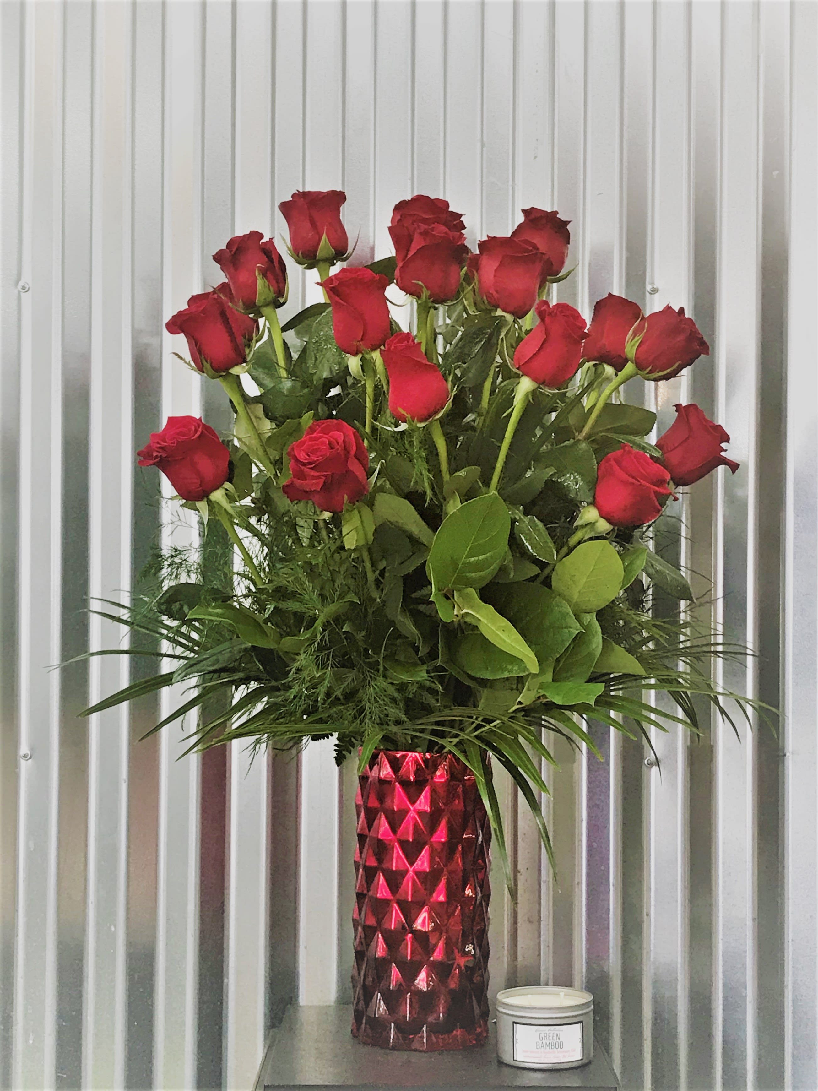 18 Red Premium Roses - This is the more - more roses, more red, more love! We design eighteen gorgeous premium roses in a vase with beautiful, lush tropical greens. 