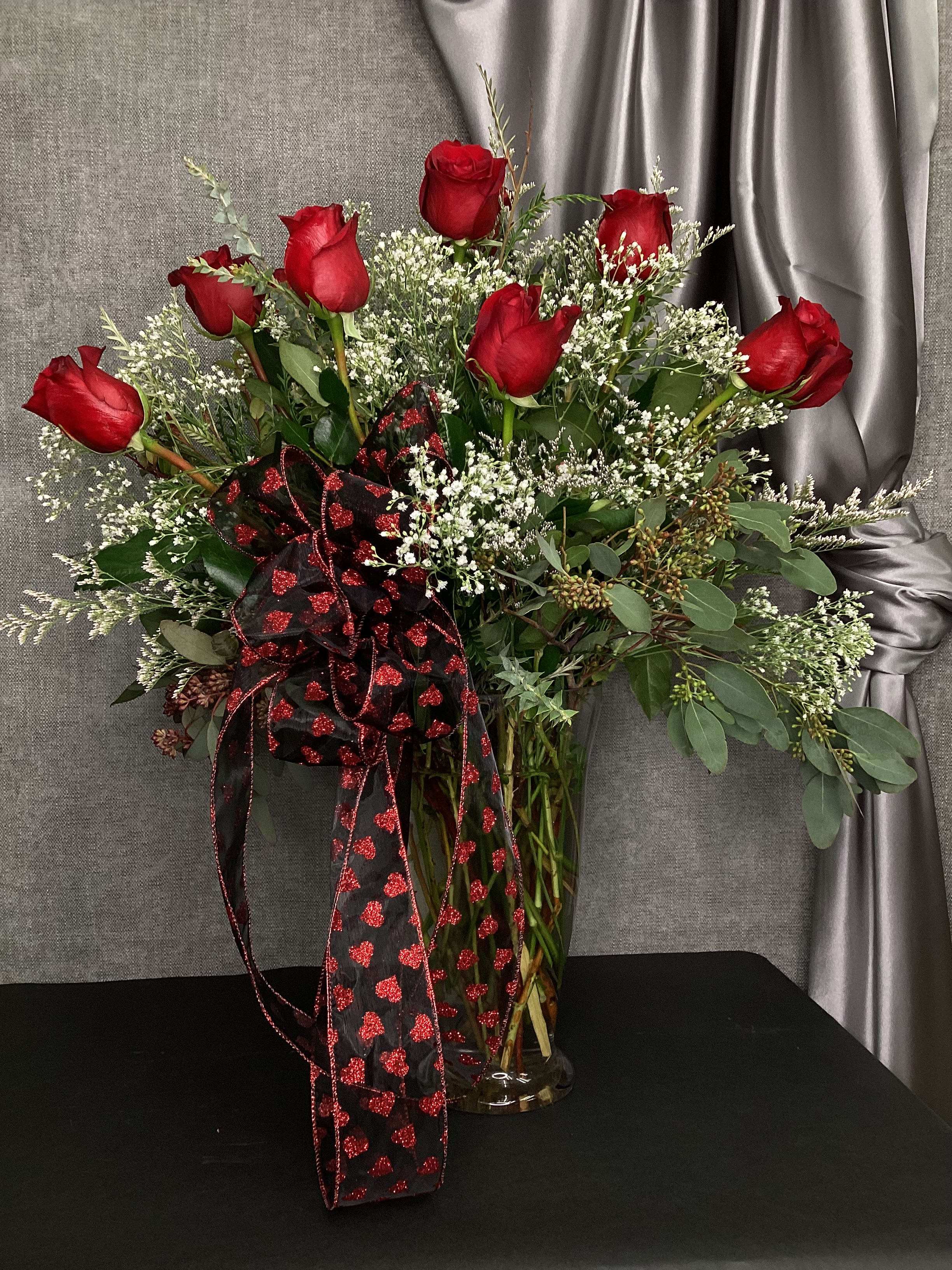 Classic Dozen Red Roses in Vase - Here is our version of the classic Dozen Rose Vase.  We use an upgraded vase along with different kinds of greenery including eucalyptus and mini myrtle.  A fun bow compliments the tried and true dozen rose vase.