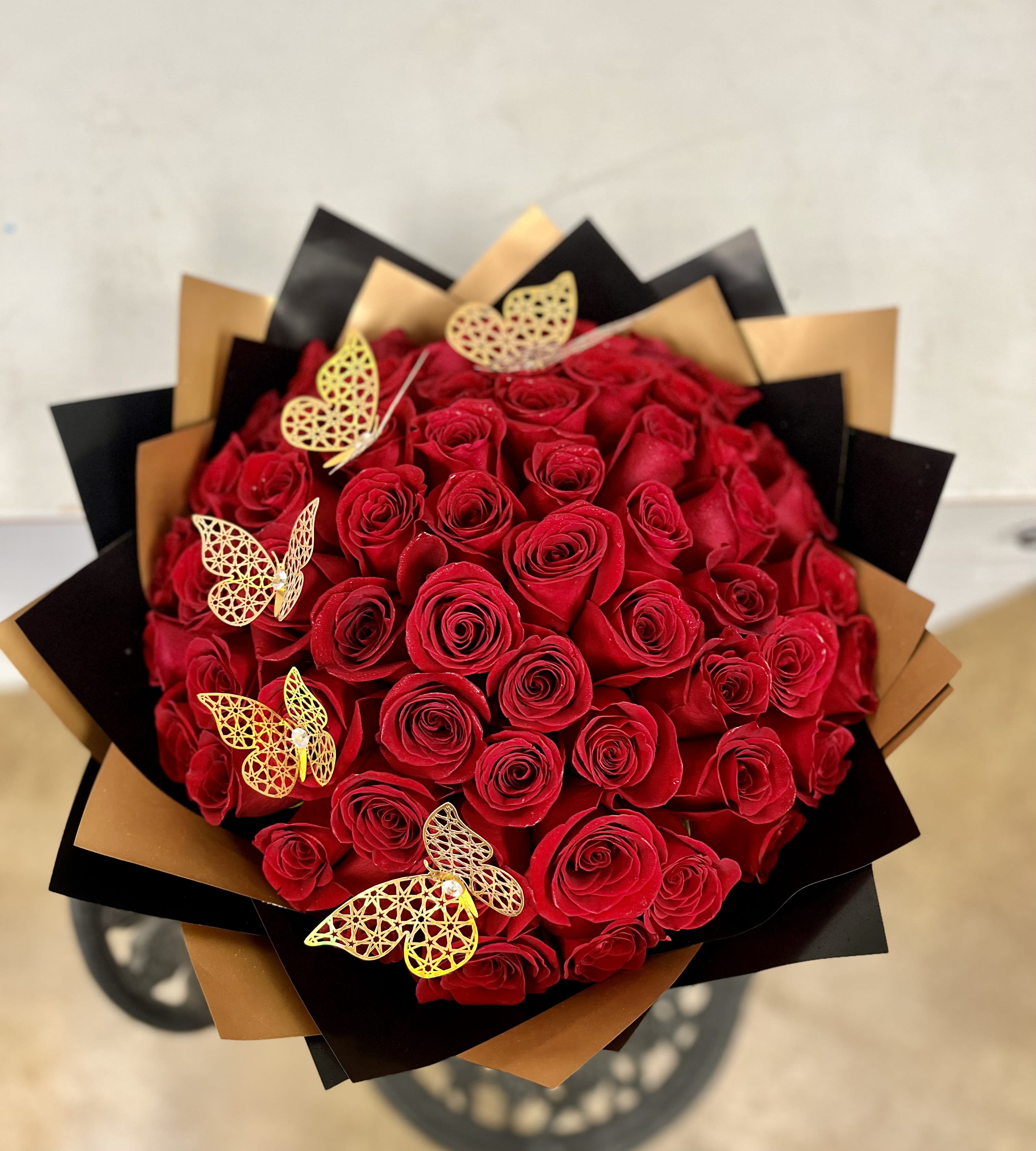 50 RED ROSE BOUQUET - The Rose Bouquet includes 50 long-stem red roses. Wrapped in black paper with a satin red bow. Includes butterflies and diamond pins. 