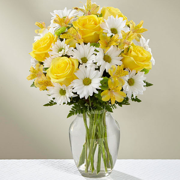 Sunny Sentiments Bouquet - Sunny Sentiment Bouquet has a warm welcoming look that will win over your special recipient with each sunlit bloom. Yellow roses and Peruvian Lilies are set to brighten their day arranged amongst bright white traditional daisies green button poms and lush greens to create a stunning presentation. Arriving arranged to perfection in a clear glass vase this fresh flower bouquet is ready to help you send your sweetest thank you thinking of you or get well wishes. 