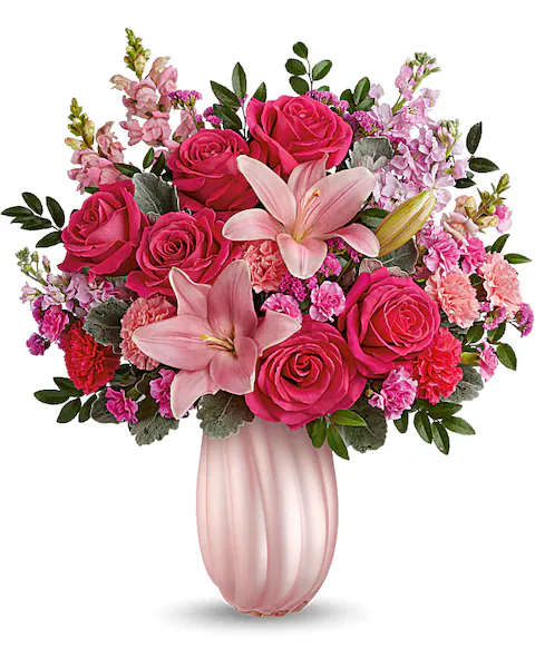 Rosy Swirls Bouquet - Capture Mom's heart with our pearlescent glass vase, radiating elegance and charm, paired with a bouquet of pink roses and lavender blooms, a delightful Mother's Day surprise she'll cherish. Create magic for Mom with our pearlescent glass vase, complemented by a bouquet of hot pink roses, pink asiatic lilies, light pink and hot pink carnations, miniature carnations, pink snapdragons, light pink stock, raspberry sinuata statice, huckleberry, and dusty miller, a radiant Mother's Day surprise she'll cherish.  