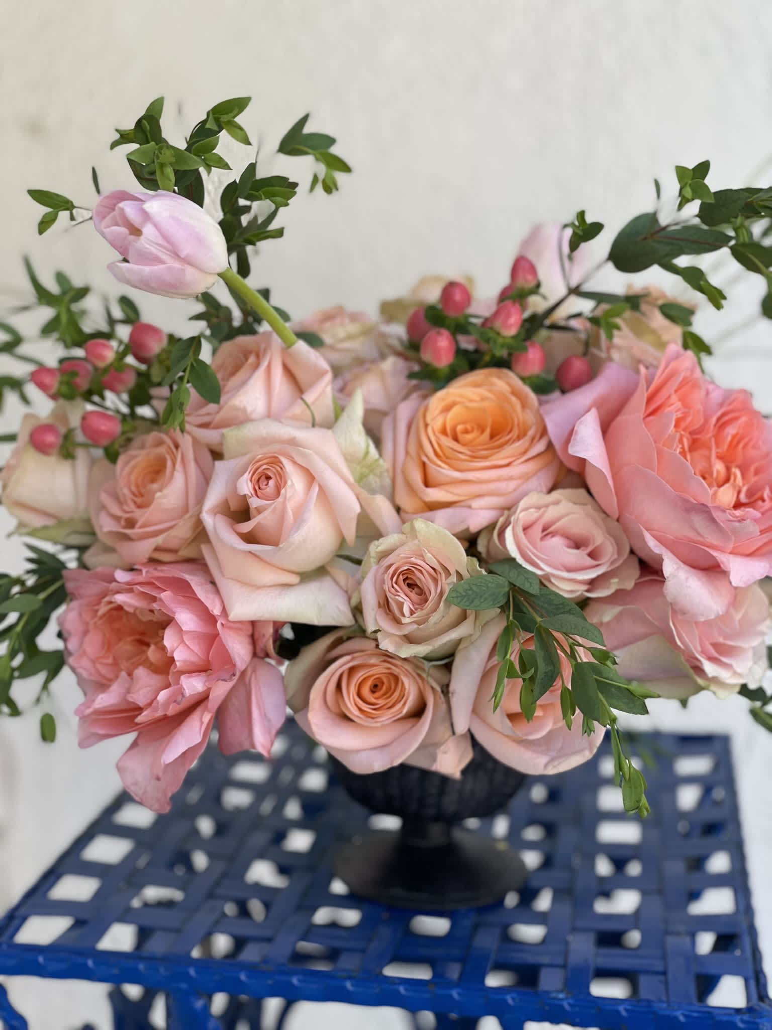 Peach Sunrise - This little arrangement packs a big punch, with its brightly colored roses in hues of peach and pink, the garden roses opening their faces to the sun, and the pale pink tulips cascading from the top. This arrangement is sure to be a showstopper and bring happiness to any person or event.