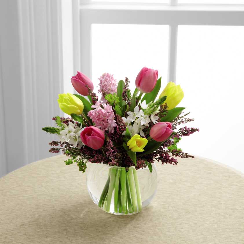 Bountiful Beauty Bouquet Bountiful Beauty Bouquet - Bright pink and yellow tulips are simply stunning arranged amongst pink hyacinth, white Star of Bethlehem stems and an assortment of lush greens. Seated in a clear glass bubble bowl vase, this bouquet creates a warm wish.