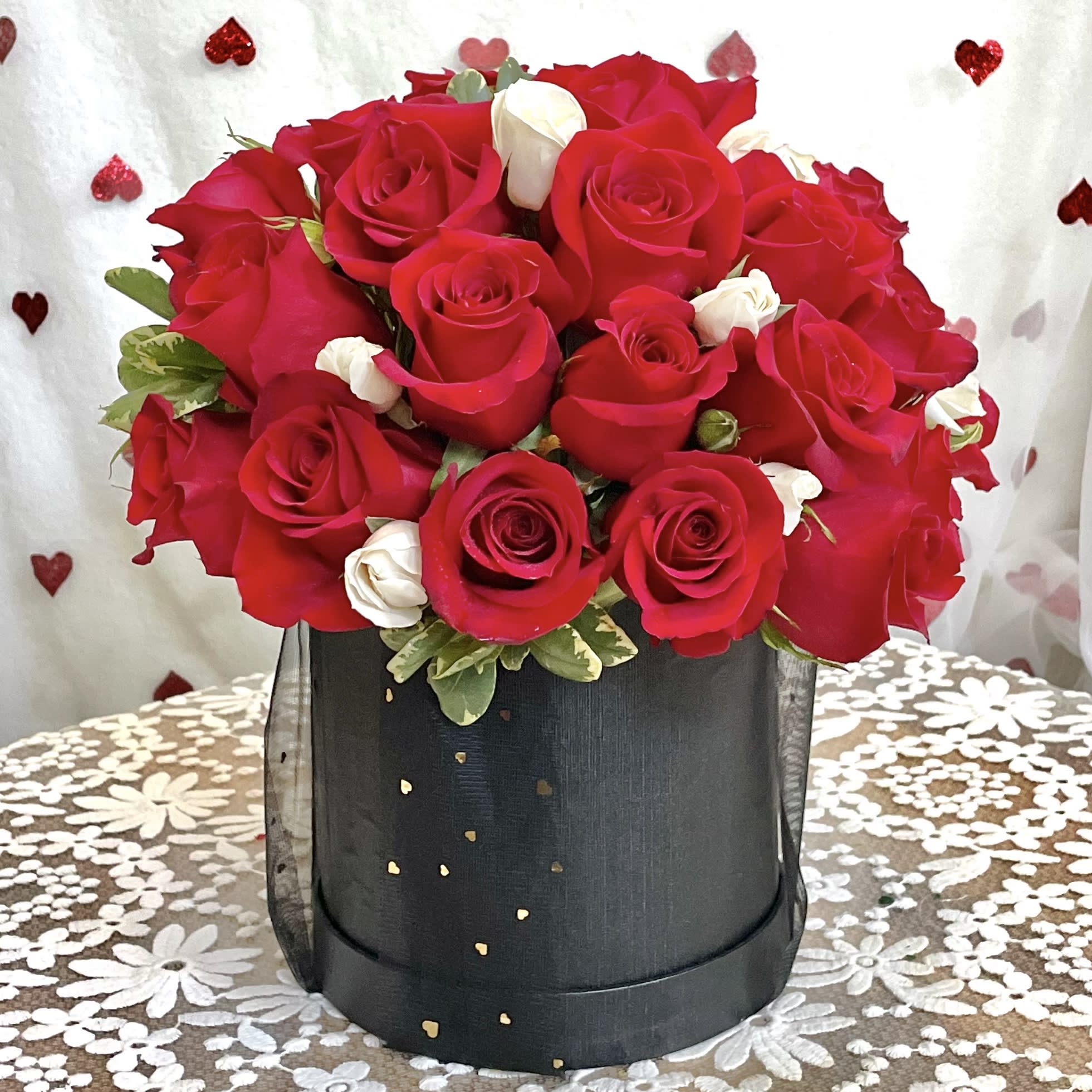 Rose Amore Hat Box - Over two and a half dozen red roses dotted with delicate white baby roses fill an elegant and reusable hat box-style container. Yes, a very romantic gift— that’s amore!