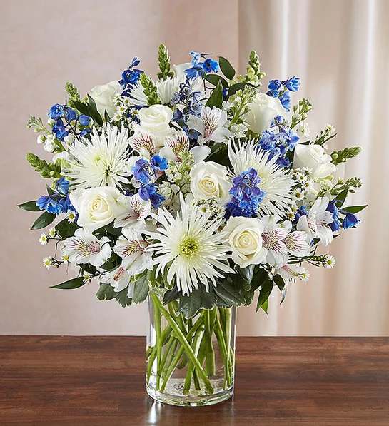 Sincerest Sorrow  Blue &amp; White - A sincerity of sentiment means so much to those grieving. Our bountiful, heavenly blue and white bouquet features a soothing mix of blue delphinium, alstroemeria, and white roses, hand-designed inside a classic clear glass vase. When sent to a service or to the home of family or friends, it makes a genuinely heartwarming gesture.