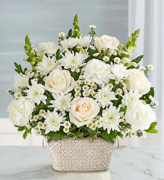 Loving Remembrance  All White - Celebrate the life of a loved one with our beautiful floral tribute. A mix of all-white blooms is a symbol of enduring love. Designed in our Remembrance Cachepot, featuring an embossed pattern and finished with a gold brushed ivory surface.
