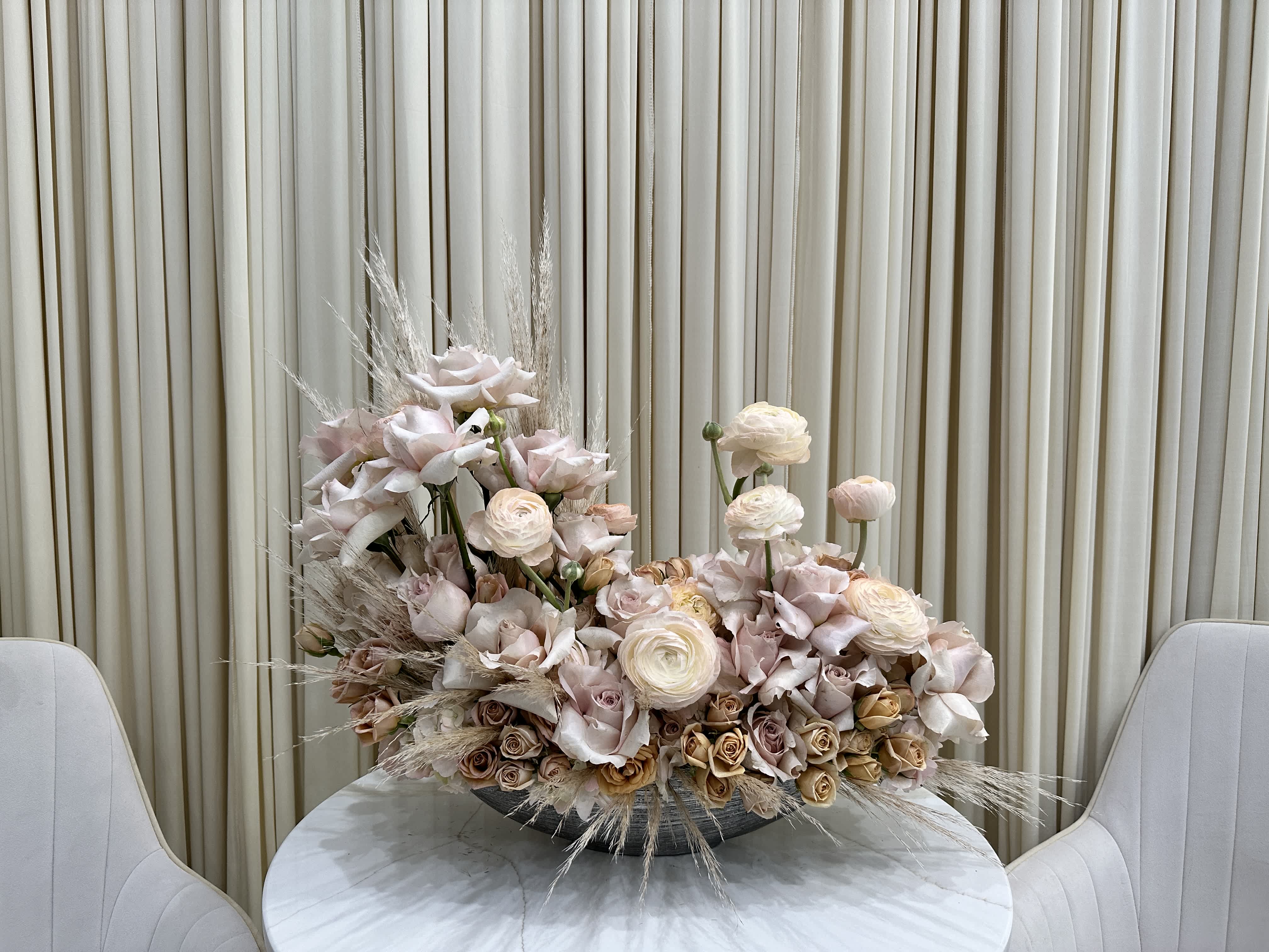 Modern Elegance - This contemporary arrangement features a stylish mix of blooms displayed in a sleek silver vase. Pink roses offer timeless beauty, while ranunculus and baby roses add a touch of youthful vibrancy. The silver vase completes the look, creating a sophisticated and fashionable gift for any occasion.