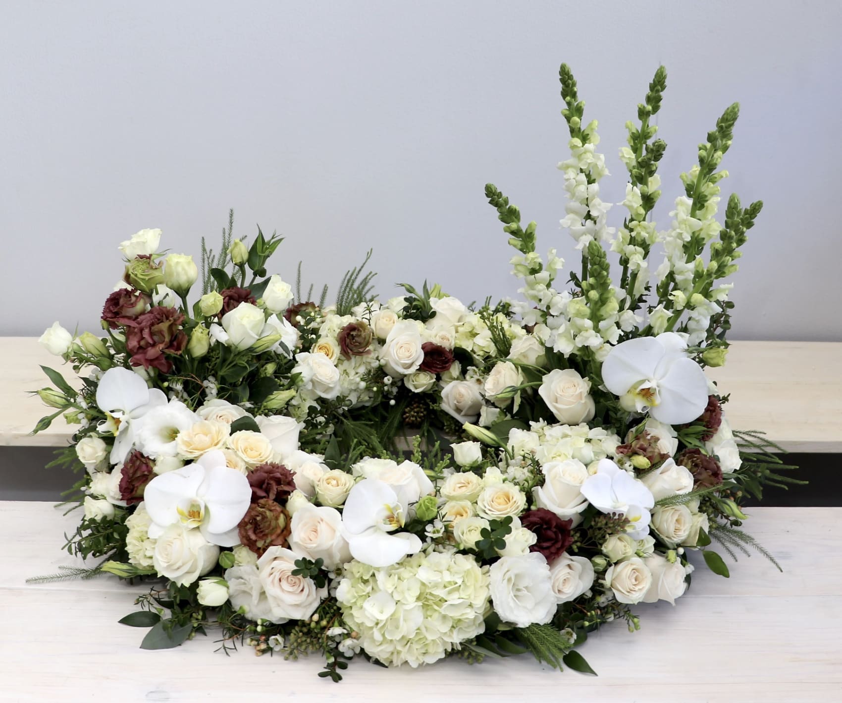 Urn Wreath  - This urn tribute wreath includes a mix of flowers, roses, and seasonal greens. In the special instruction let us know what colors you would like. Standard size is 30'', deluxe is 36'' and premium is 42''. Interior diameter is about 10'' for standard size.
