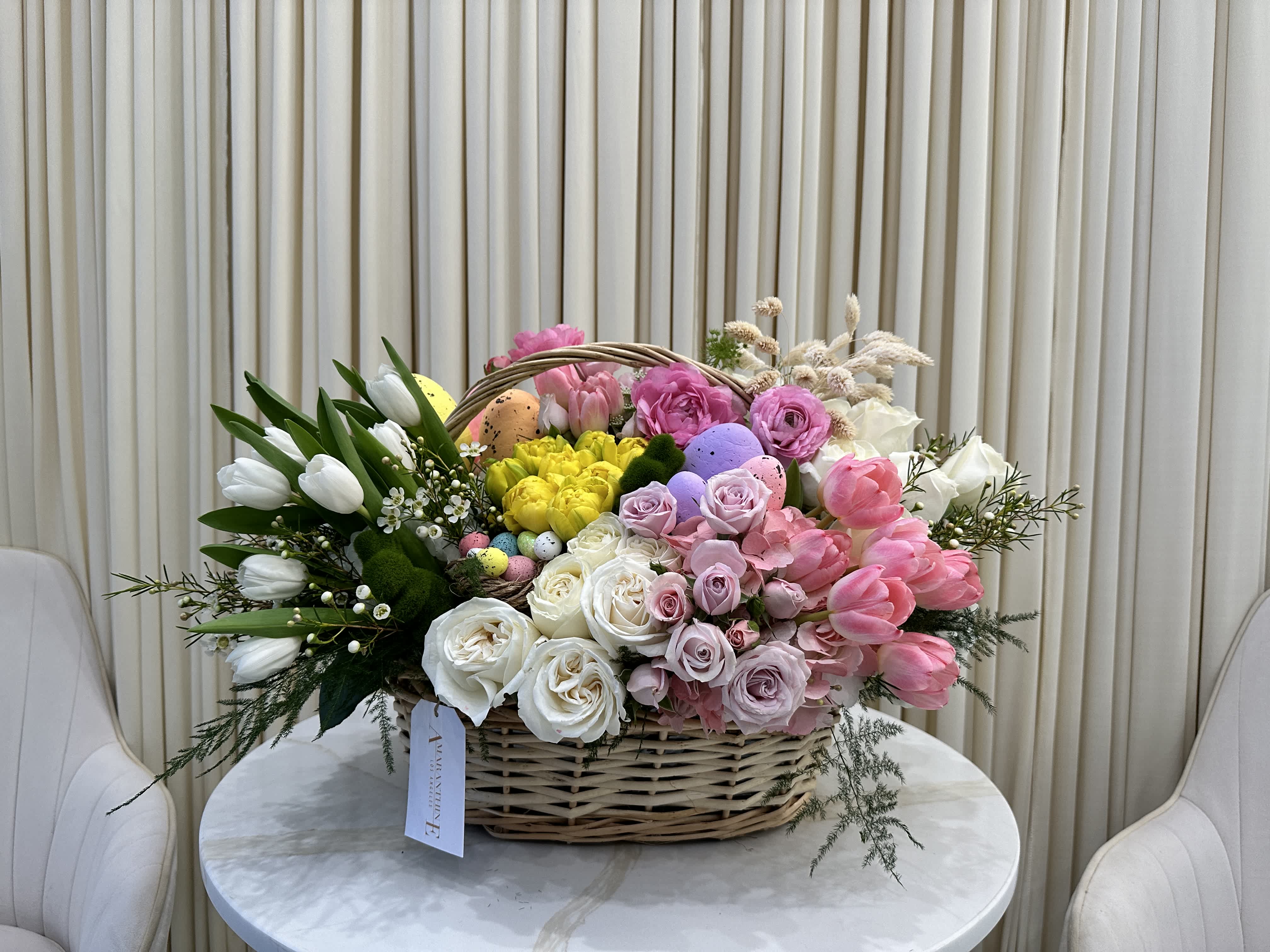 Easter Garden - Bursting with springtime colors and textures, this Easter basket captures the essence of the season.  A delightful mix of tulips, ranunculus, and roses in vibrant colors complements the adorable Easter eggs and bunny figurine, creating a festive and delightful Easter arrangement.