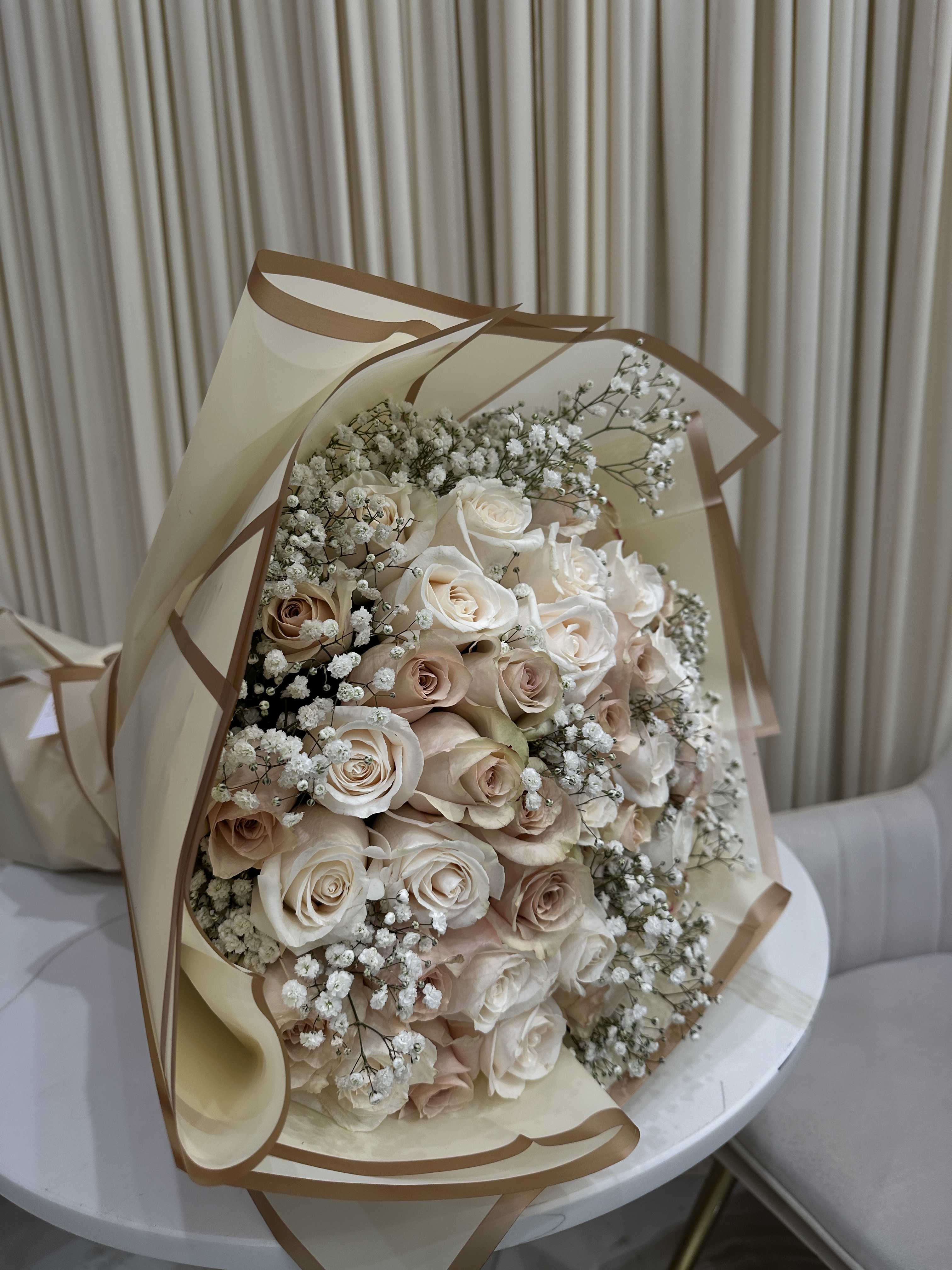 Whispering Neutrals - This delicate bouquet features 50 roses with soft baby's breath accents. The soft, neutral tones of the roses create a sophisticated and timeless look, perfect for any occasion.