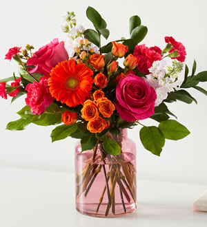 Fiesta Bouquet in Blush Vase - Deluxe - The Fiesta Bouquet is composed of a lively mix, fit to celebrate any and every moment. With a combination of vibrant flowers, this arrangement brings a pop of color and a burst of excitement as soon as it arrives.