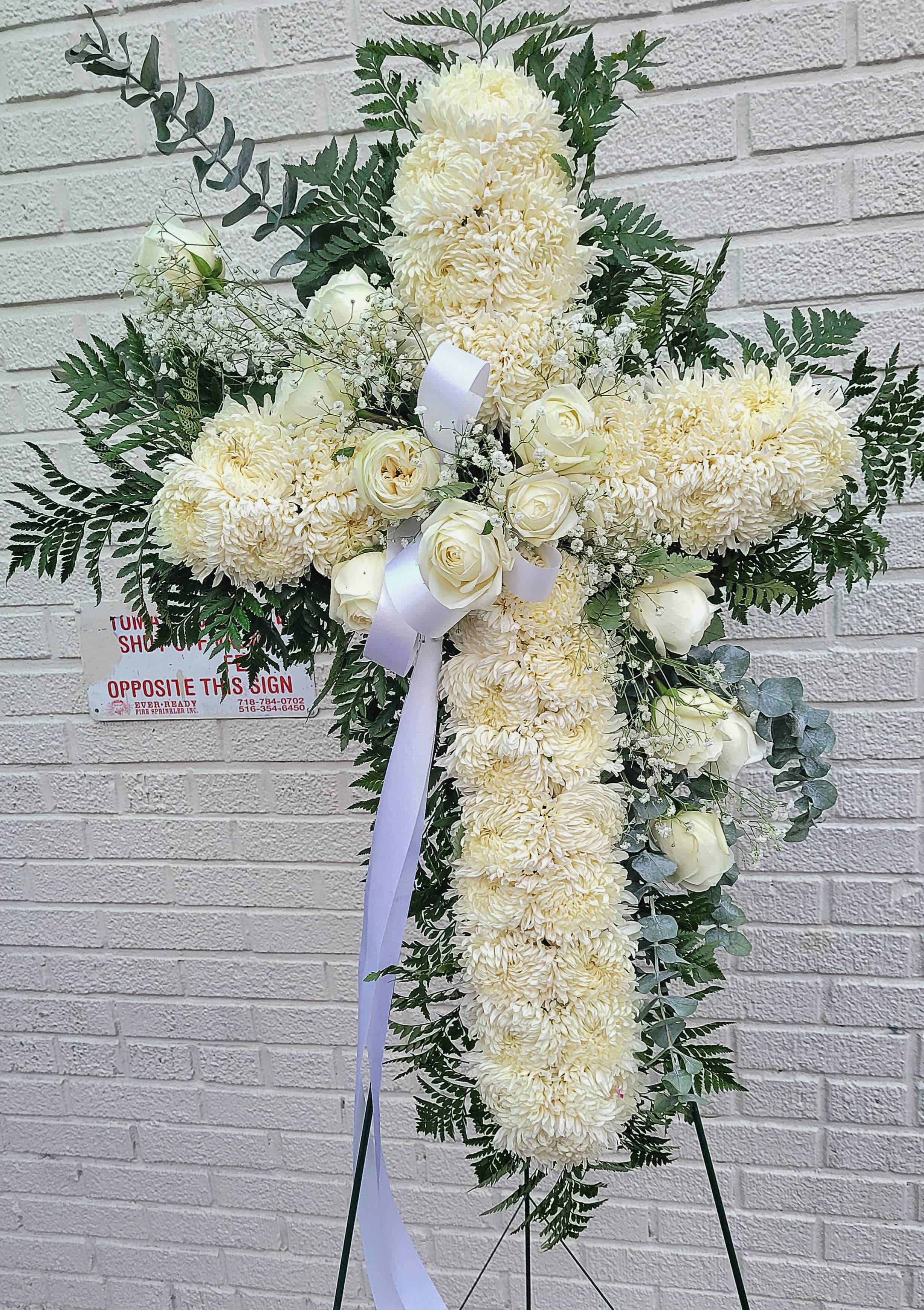 Standing cross #2 - it is made with: 30 white mums 12 white roses 2 baby breath greens  eucalyptus white bow  