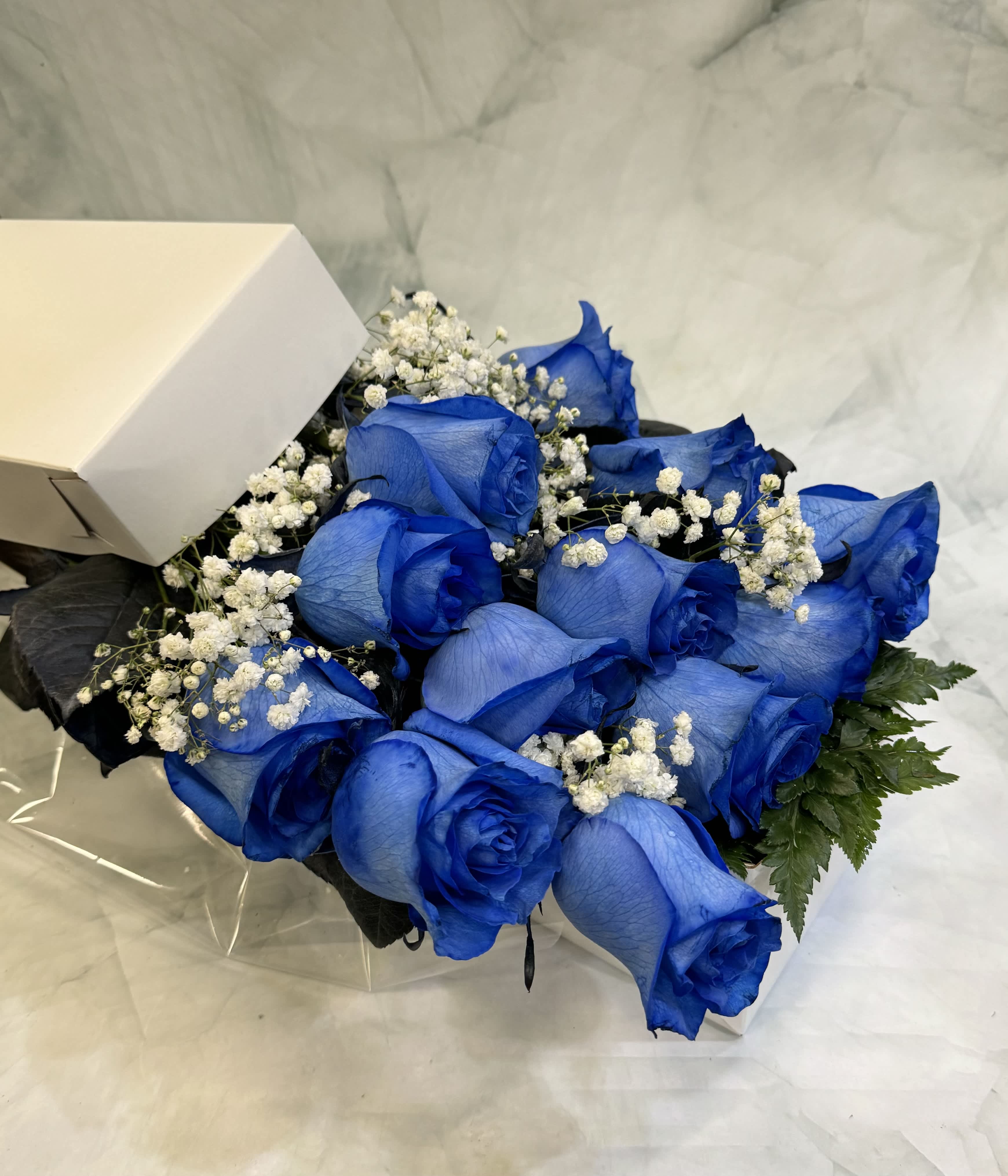 Dozen Blue Roses Gift Boxed  - This is a beautiful way to present blue Roses. This is a gorgeous display of one dozen blue Roses that are arranged in a white, long gift box that is then all wrapped up with a bow. 