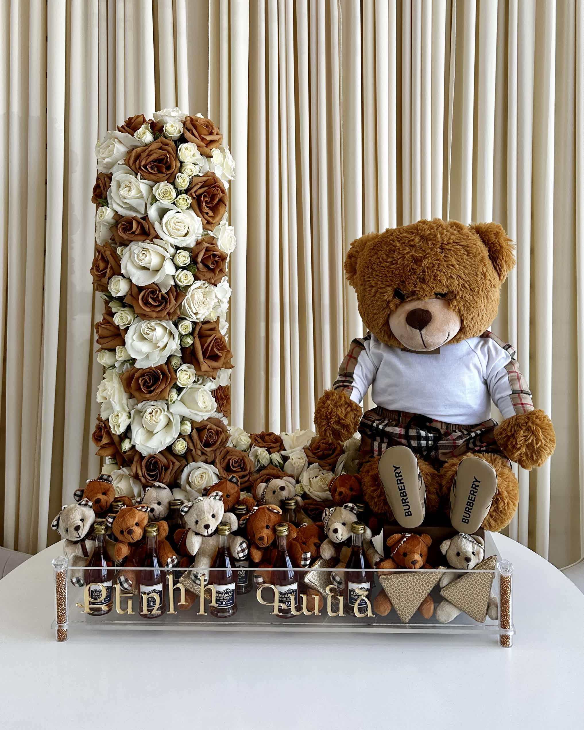 Blossoming Love - !!! Large teddy bear, writing on Tray, and items in tray not included!!! Celebrate the joyous arrival of a new baby with our &quot;Blossoming Love: Baby Edition&quot; letter flower arrangement! This delightful creation comes in an elegant acrylic tray, adorned with a cuddly teddy bear and thoughtfully designed to hold a selection of personalized gifts provided by you.  Share your love and warm wishes with the new parents and their bundle of joy as they embark on this beautiful journey of parenthood. Customize the arrangement with items of your choice, making it a truly unique and heartwarming gift.  With a charming combination of fresh, vibrant blooms and a cute teddy bear, &quot;Blossoming Love: Baby Edition&quot; is a perfect way to welcome the little one into the world and create lasting memories for the growing family. Spread happiness and congratulations with this special arrangement designed to celebrate love and new beginnings.