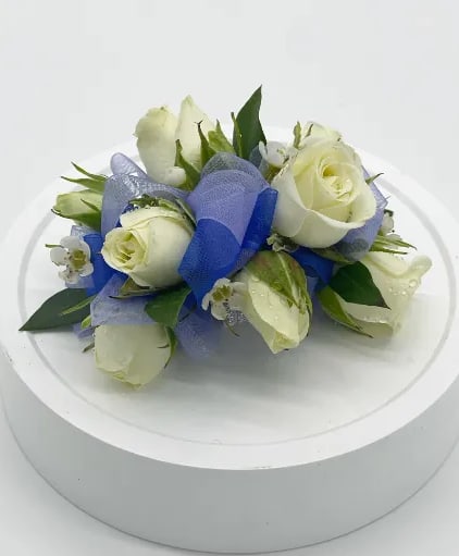 Spray Rose Corsage Basic Corsage - This is a basic, white spray rose corsage. You may indicate a different rose color as well. When ordering, please indicate desired ribbon color! This corsage includes seasonal filler flowers and greens with an elastic tie. A deluxe corsage will include rhinestones, and a premium corsage will include an upgraded rhinestone bracelet or beaded band. A designer will contact you after your order to confirm your choices and seasonal availability.
