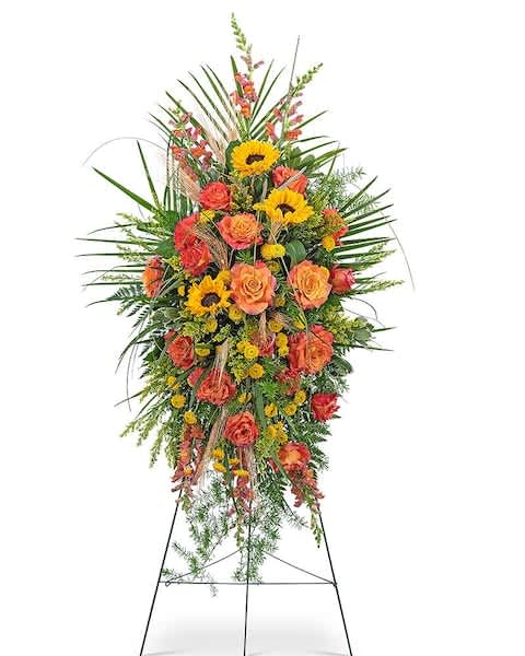 Sunset Reflections Standing Spray - The Sunset Reflections Standing Spray is brilliant and beautiful, featuring orange roses, snapdragons, button spray mums, sunflowers, solidago, and premium foliage. Sunflowers represent pure love and adoration, which makes this floral standing spray the perfect accent to a funeral or celebration of life ceremony. The Sunset Reflections Standing Spray is a radiant way to celebrate and reflect on an amazing life.
