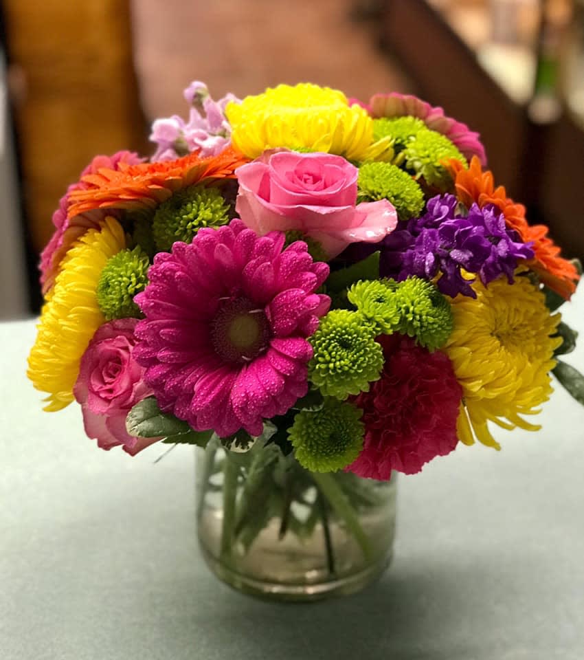 Pop of Summer Flowers - In a short cylinder we have beautiful gerberas, vibrant roses, and apple green hydrangea that creates a stunning, vibrant arrangement of  summer colors.