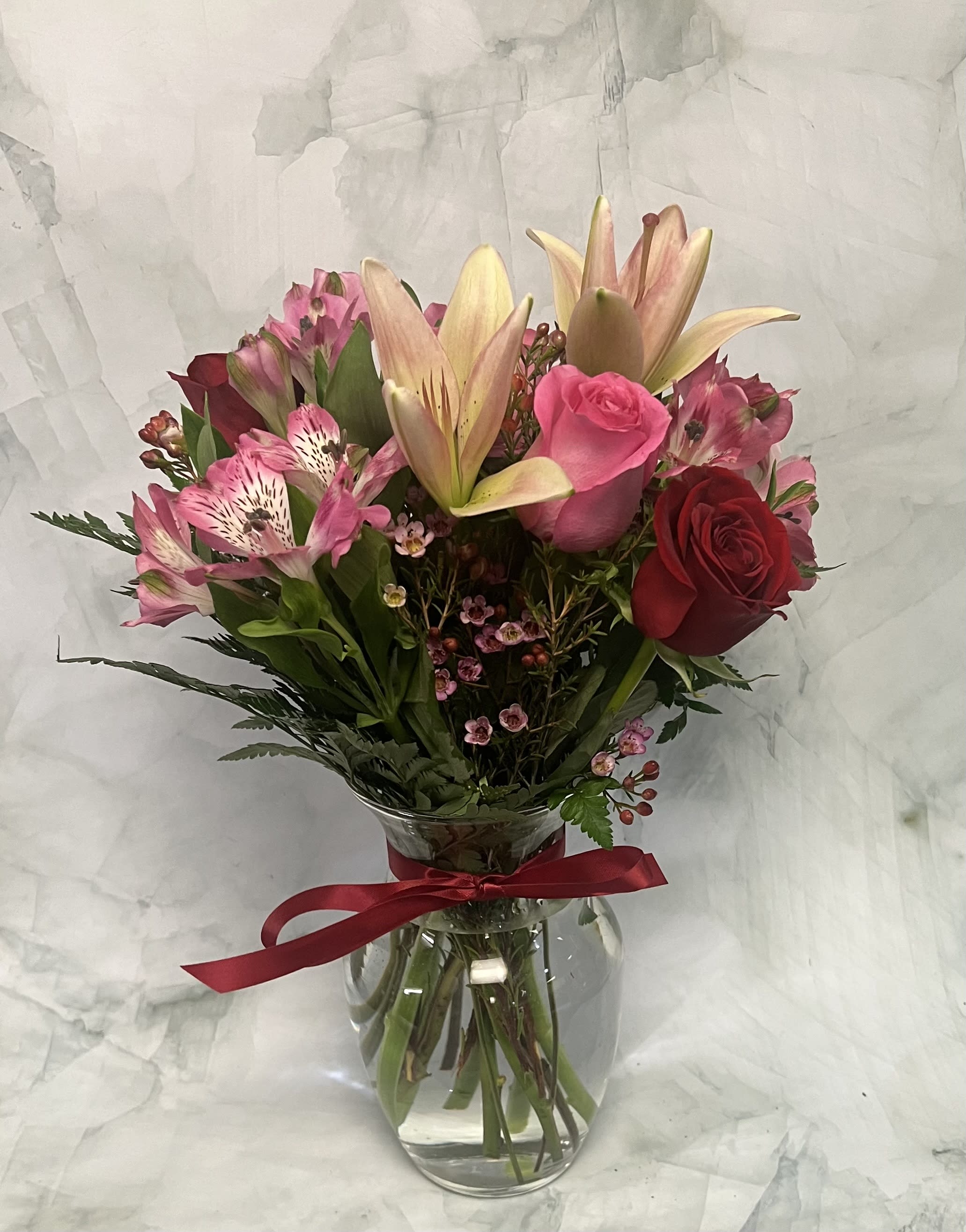 Loving Lilies and Romantic Roses - This arrangement is the perfect symbol of love. This includes pink Lilies, Peruvian Lilies, red Roses and pink Roses with a touch of pink Wax flower that ties the whole arrangement together. Whether it is for an anniversary or a just because occasion, this arrangement is the perfect combination of love and romance. 