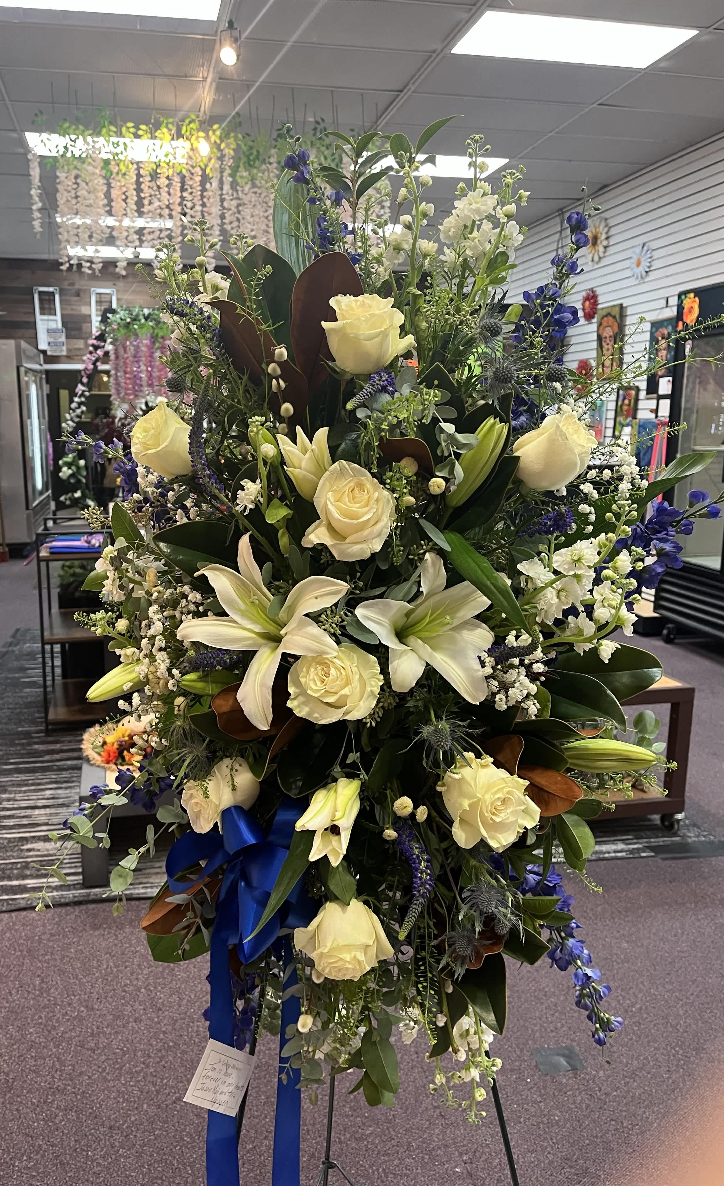 Peaceful Passage Peaceful Passage - The "Peaceful Passage" arrangement blends white roses, alstroemerias, carnations, and hypericum with blue delphiniums, stock, and baby's breath for a serene and dignified tribute.