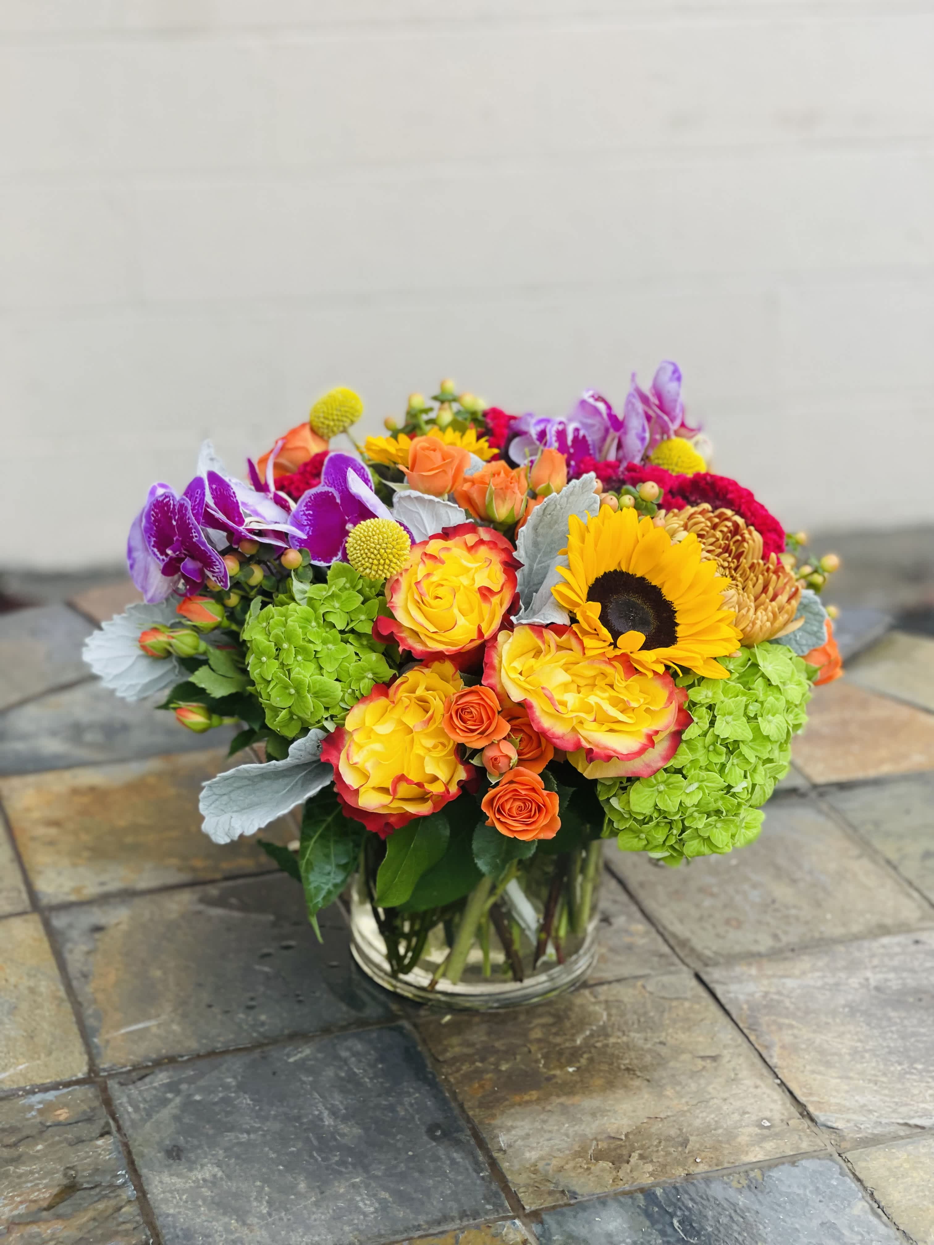 Mix yellow spring vase - This beautiful vase comes in a 6 x 6 with yellow gold roses, green hydrangeas, sunflowers, vibrant orchids, and other garden flowers.