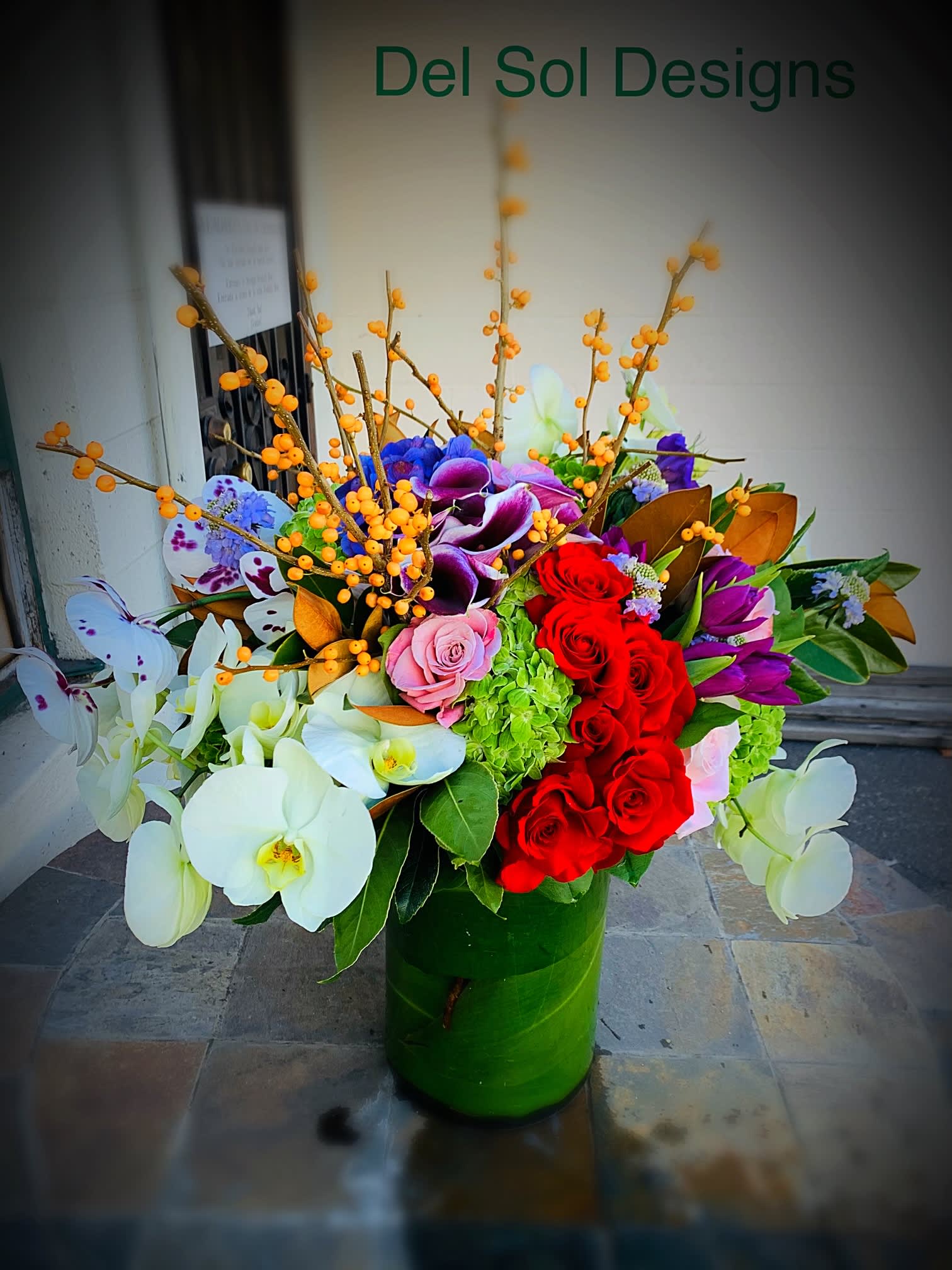 Tall vase with tea leaves covered vase and beautiful flowers - This is a tall covered base with large tea leaves with beautiful large orchids garden roses, Calla lilies with nice greens. 