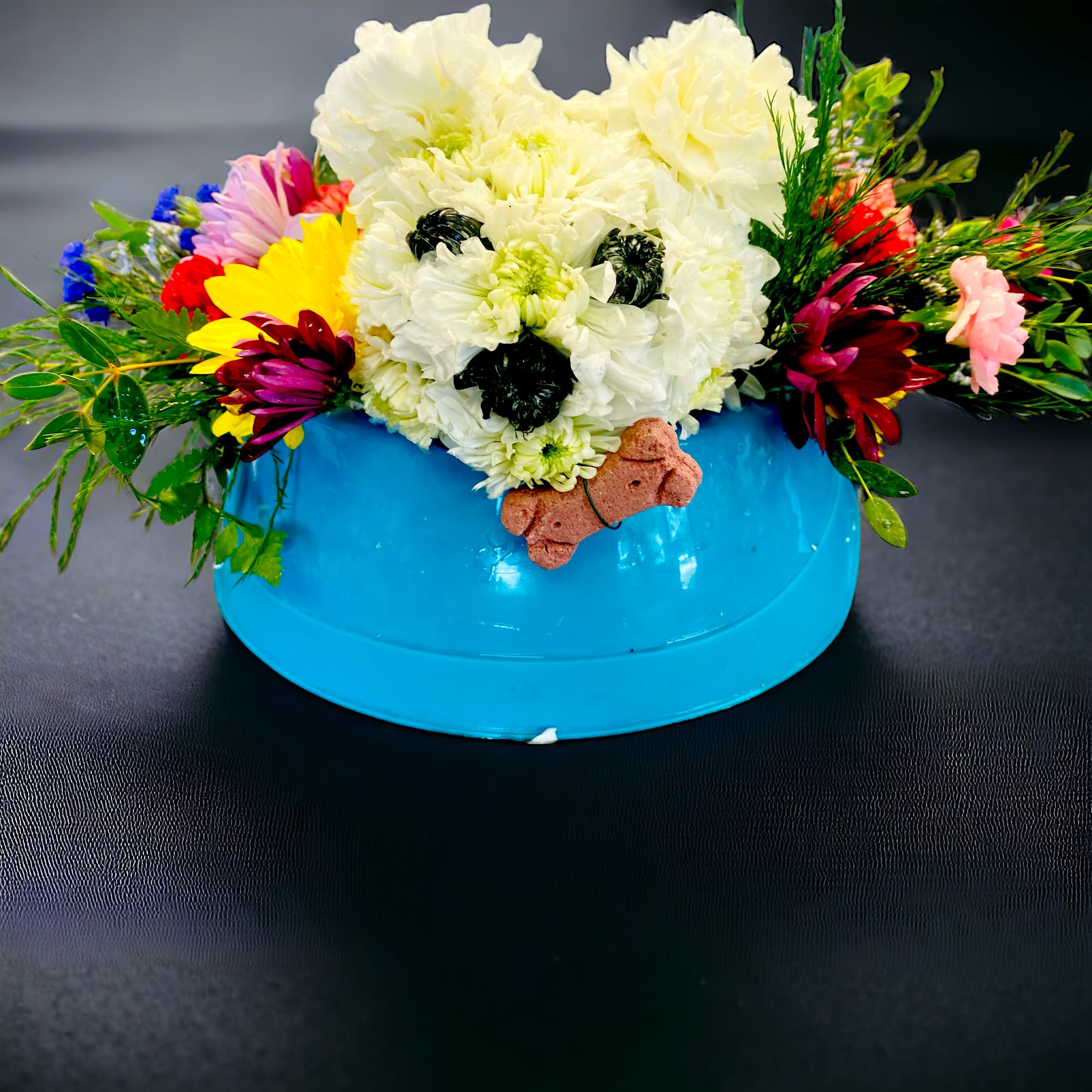 Toby - A true specialty creation made for any lover of dogs. This carnation and cushion mums dog, is made with the most love and care due to the inspiration holds a special place in my own heart. This dog was created and designed from the original Toby that was apart of my family, and to continue to make this creation of mine and bring joy to others is such an honor and a joy of mine. Toby continuously is created in a dog bowl with his one real treat he carries with him as he lays in a garden of mix flowers and greenery.  (Garden flowers may vary, in color, size, and variety) 