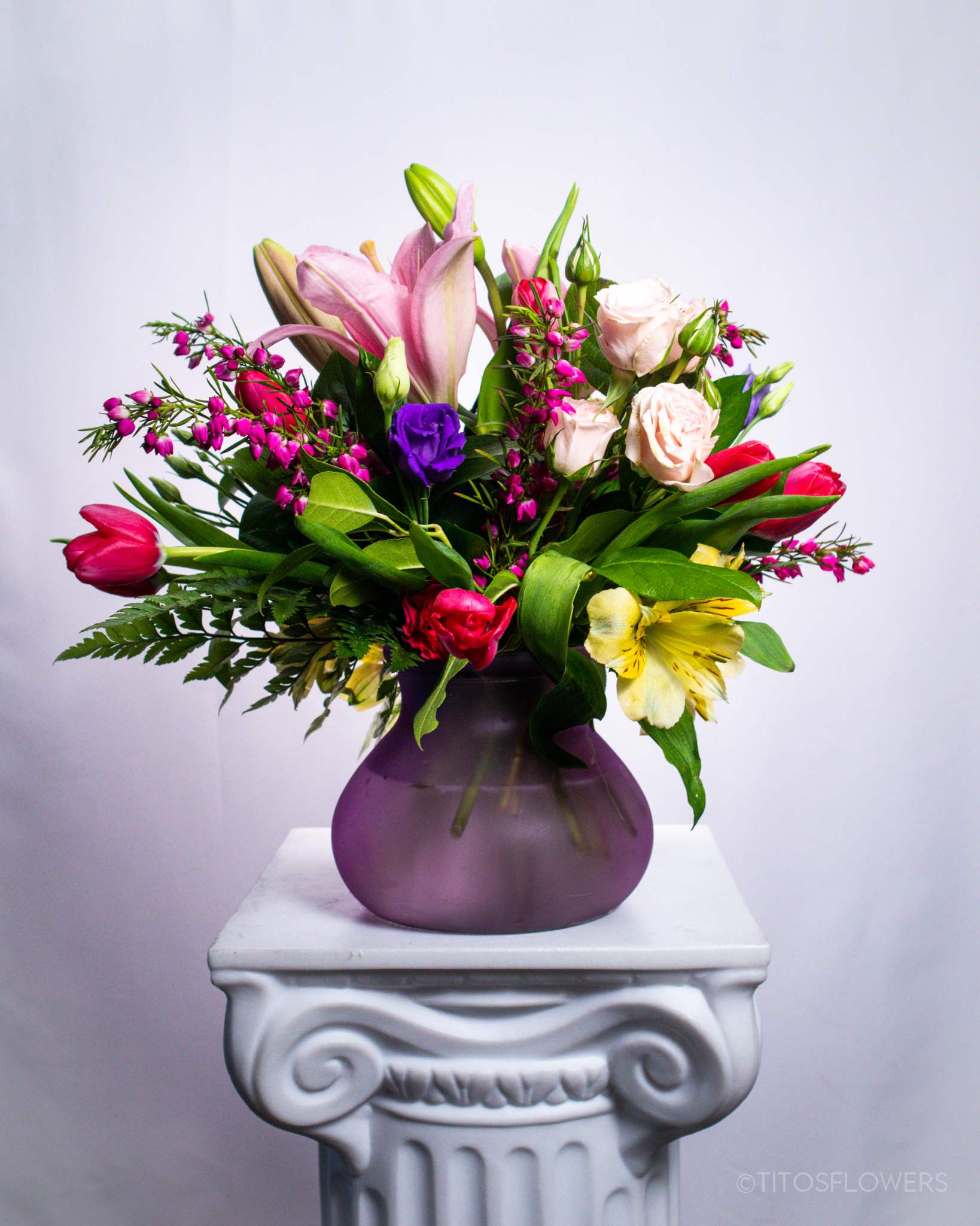 Mother’s Day 002 - &quot;Enchanted Spring&quot; is an exquisite arrangement that captures the essence of the season with a delicate combination of tulips, lilies, and spray roses. With its vibrant color palette and natural elegance, this arrangement is perfect for brightening any space and conveying joy and freshness. Ideal as a gift to celebrate special occasions or simply to add a touch of beauty to your home or office.