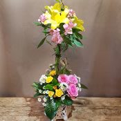 Laced Topiary - A fun topiary made of Asiatic Lilies and Alstroemeria wrapped in colorful ribbons, based with  spray roses, mums and seasonal blossoms in a cut ceramic vase that doubles as a candle hurricane.  