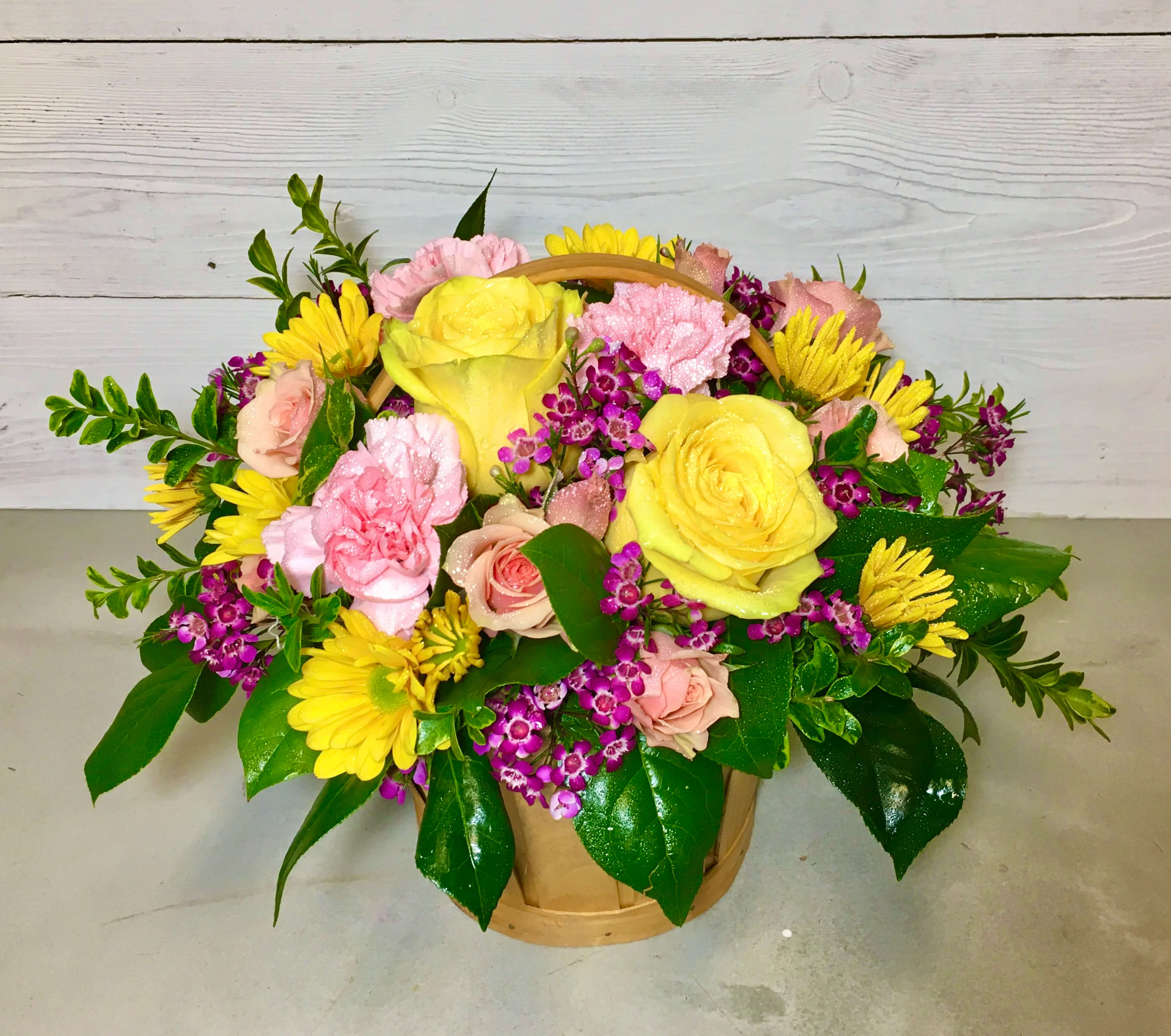 Spring Basket  - This arrangement features a mix of spring flowers including roses, carnations, daisies, greens, and filler in a basket. Colors may very. Due to various factors, substitutions may apply. If substitutions are necessary, the utmost care and attention will be given to your order to ensure it is as similar as possible to the requested item