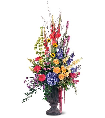 Grand Sentiments Grand Sentiments - If you want to express your deepest sentiments in a grand way this majestic arrangement urn arrangement of striking flowers is perfect. One arrangement arrives with blue delphinium pink gerberas orange roses yellow stock and sunflowers in a rental urn.