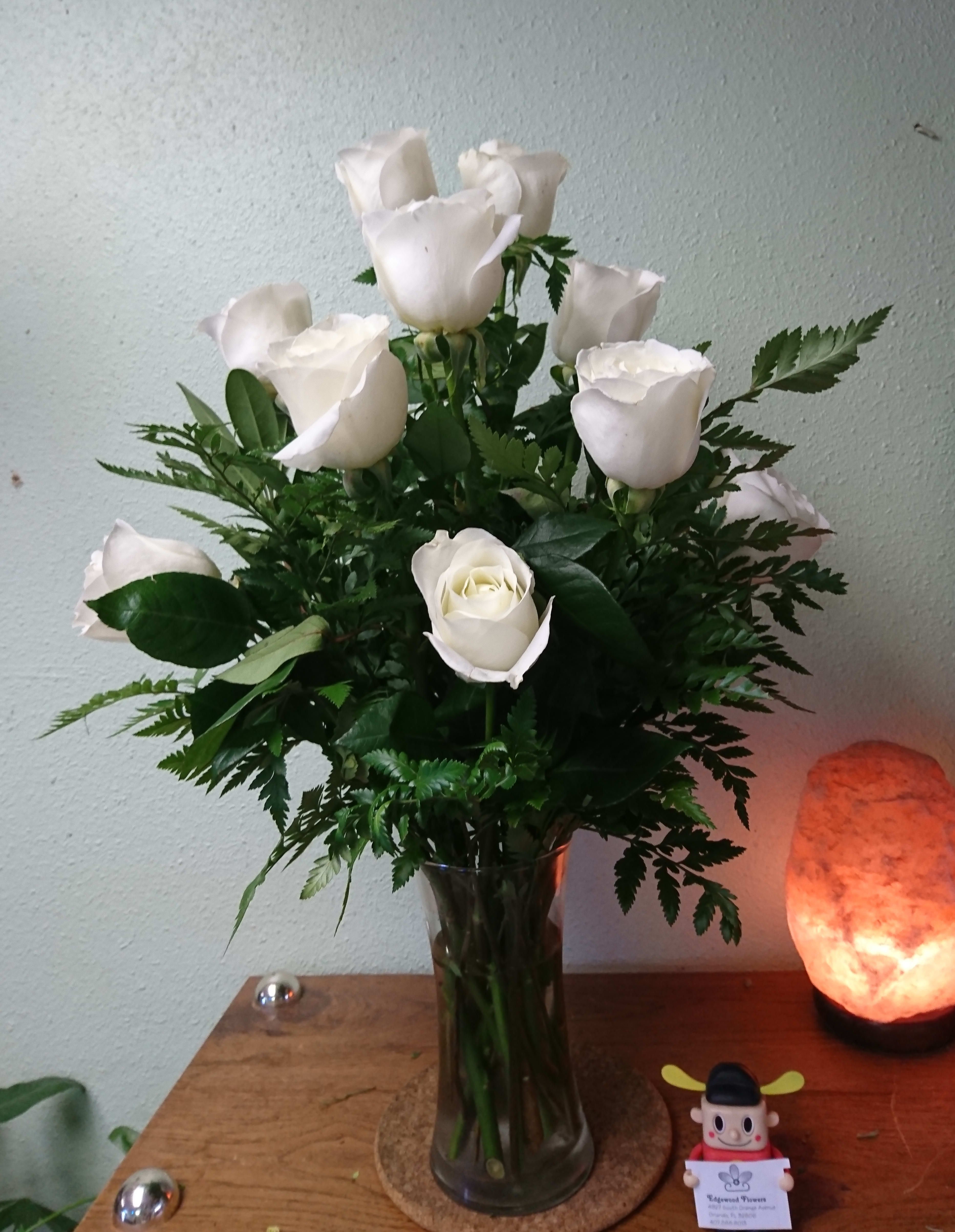 The White Rose Bouquet - The White Rose Bouquet offers a rare beauty of simple elegance that will bring peace and comfort to your special recipient during their time of grief and loss. A bouquet of white roses arrives accented by lush greens gorgeously arranged in a clear glass vase to create a graceful way to display your most sincere sympathies.
