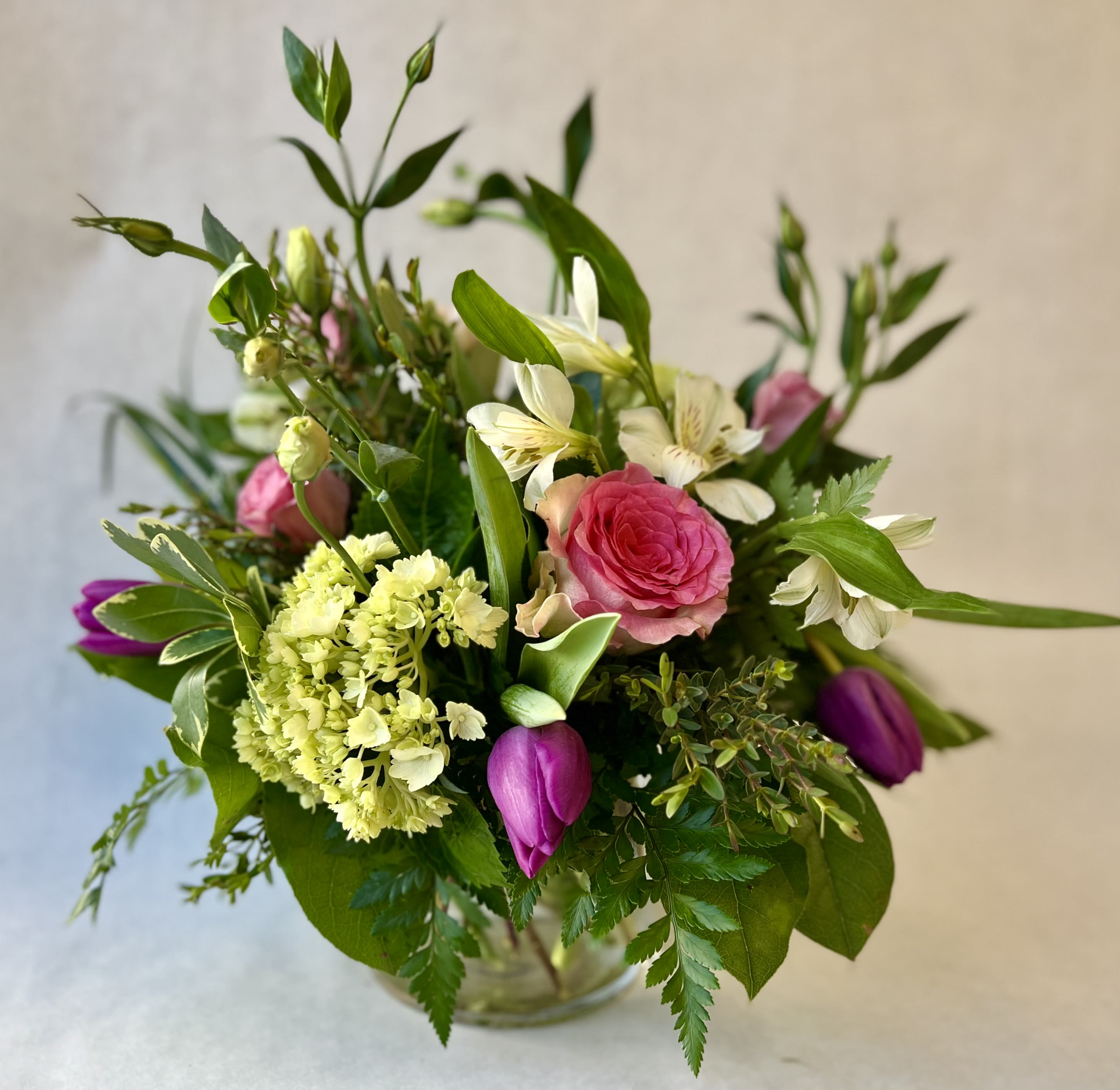 Butterfly Kisses - A lovely mixed bouquet featuring bright and cheery seasonal blooms arranged in a clear glass vase. 