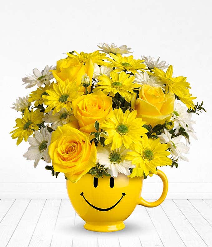 Be Happy Bouquet - Sending someone a smile is as easy and sending them this smiling flower bouquet. The Be Happy Bouquet is the perfect give to turn someone's day around. This yellow smiley face mug is overflowing with seasonal yellow flowers such as daisies and roses, accompanied by white daisies sprinkled in. The best part is that the mug, after a good washing, is reusable, this this really will bring them a smile day after day. Perfect for morning coffee or afternoon tea, the this yellow treat is worth giving. 
