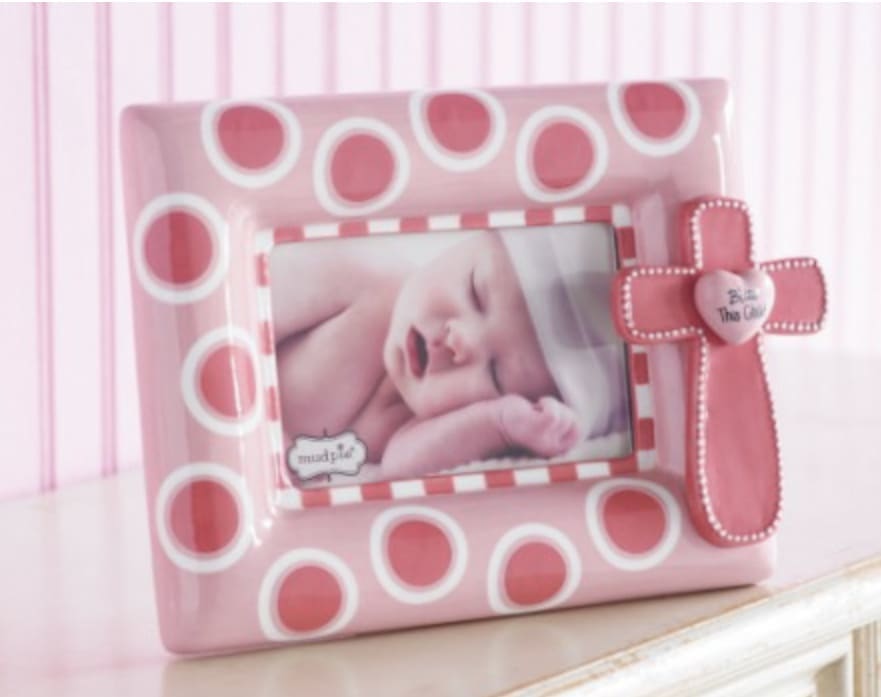 Pink Ceramic Cross Frame by Mud Pie Pink Ceramic Cross Frame by Mud Pie - The only way this darling pink baby frame can get any cuter is by displaying your baby girl's precious photo in it. The hand painted ceramic frame is designed in large dots with a dimensional cross attachment that features beaded detail and a raised heart that reads "Bless This Child".
