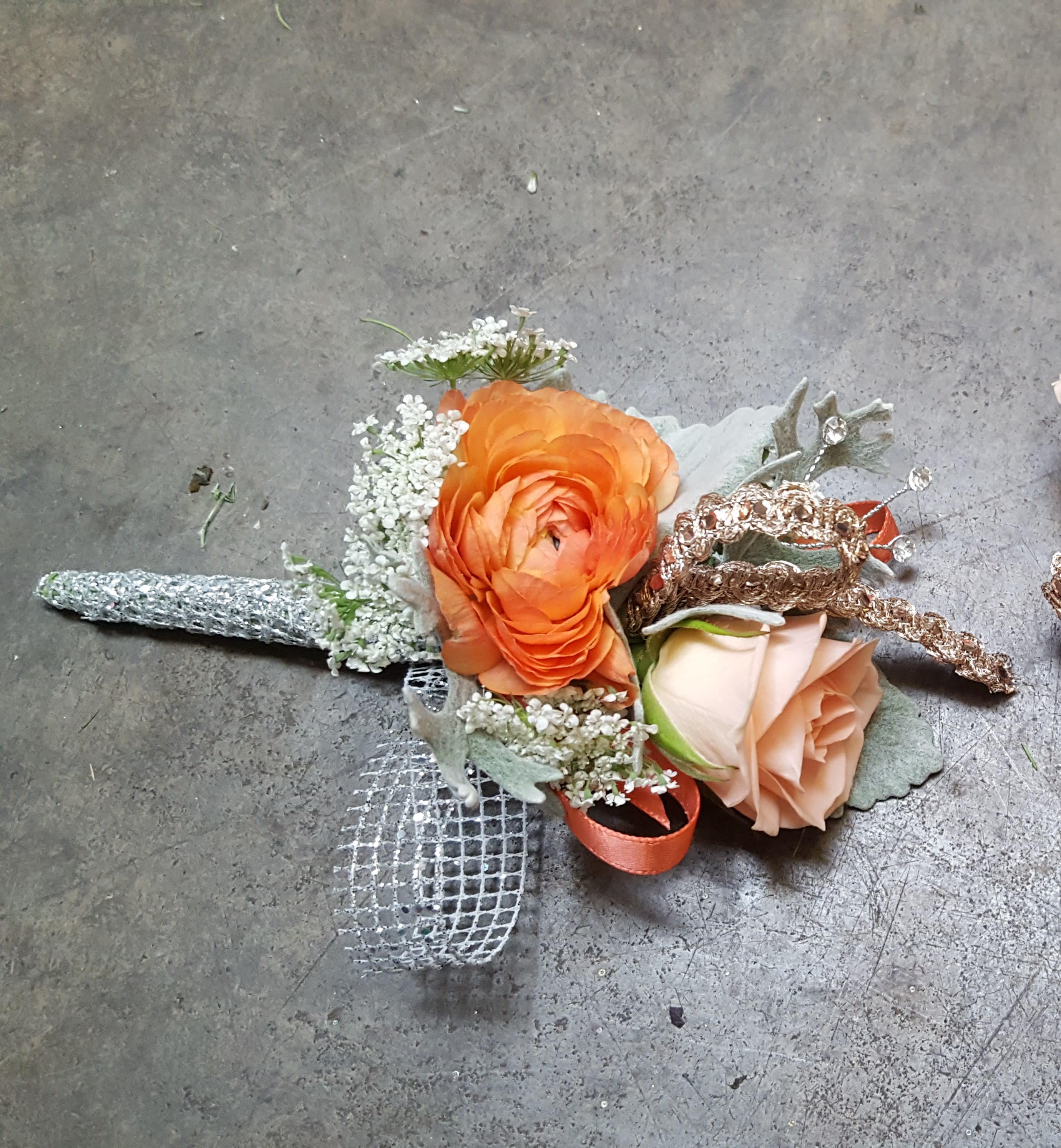Peachy Keen Boutonniere Peachy Keen Boutonniere - Select this boutonniere of a single peach spray rose and a single orange ranunculus with ribbon accents. ALL PROM FLOWERS ARE AVAILABLE IN COLORS PICTURED OR A CUSTOM SELECTION. CHOOSE YOUR FLOWER COLORS, RIBBON COLOR AND ANY ADD ONS. FOR QUESTIONS CALL A FRIENDLY SALES REPRESENTATIVE AT STRELITZIA FLOWER CO.