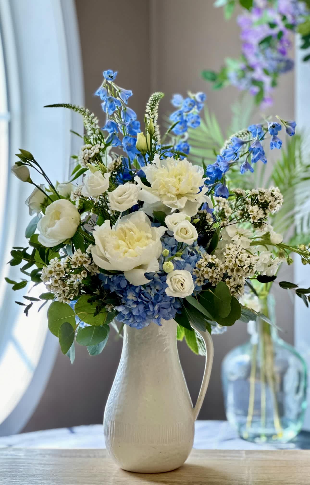 Ocean Dream's - Two gifts in one, a beautiful fresh flower arrangement and a keepsake white ceramic pitcher! Fresh flowers includes; hydrangea, lisianthus, wax flower, peonies, stock, delphinium, veronica and mixed greenery throughout. Flowers &amp; Colors may vary! AVAILABLE FOR LOCAL DELIVERY ONLY!!!