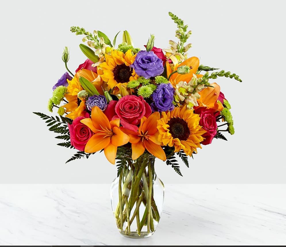 Bright and Sunny Bouquet - The Best Day Bouquet is ready to create a moment your recipient will always remember! This instant mood booster is the perfect combination of bright, bold colors and gorgeous florals. A mix of roses, lilies, snapdragons and button pompons makes this day, their best day. Handcrafted in a clear glass vase, this fresh flower arrangement is made just for you to help you send your warmest birthday or get well wishes to your favorite friends and family