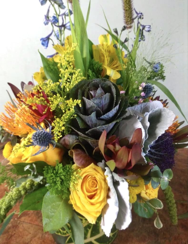 Majestic Fall  - This arrangement contains yellow roses, blue thistle, solidaster, yellow astromedia, kale, and safari sunset all arranged in a glass vase.